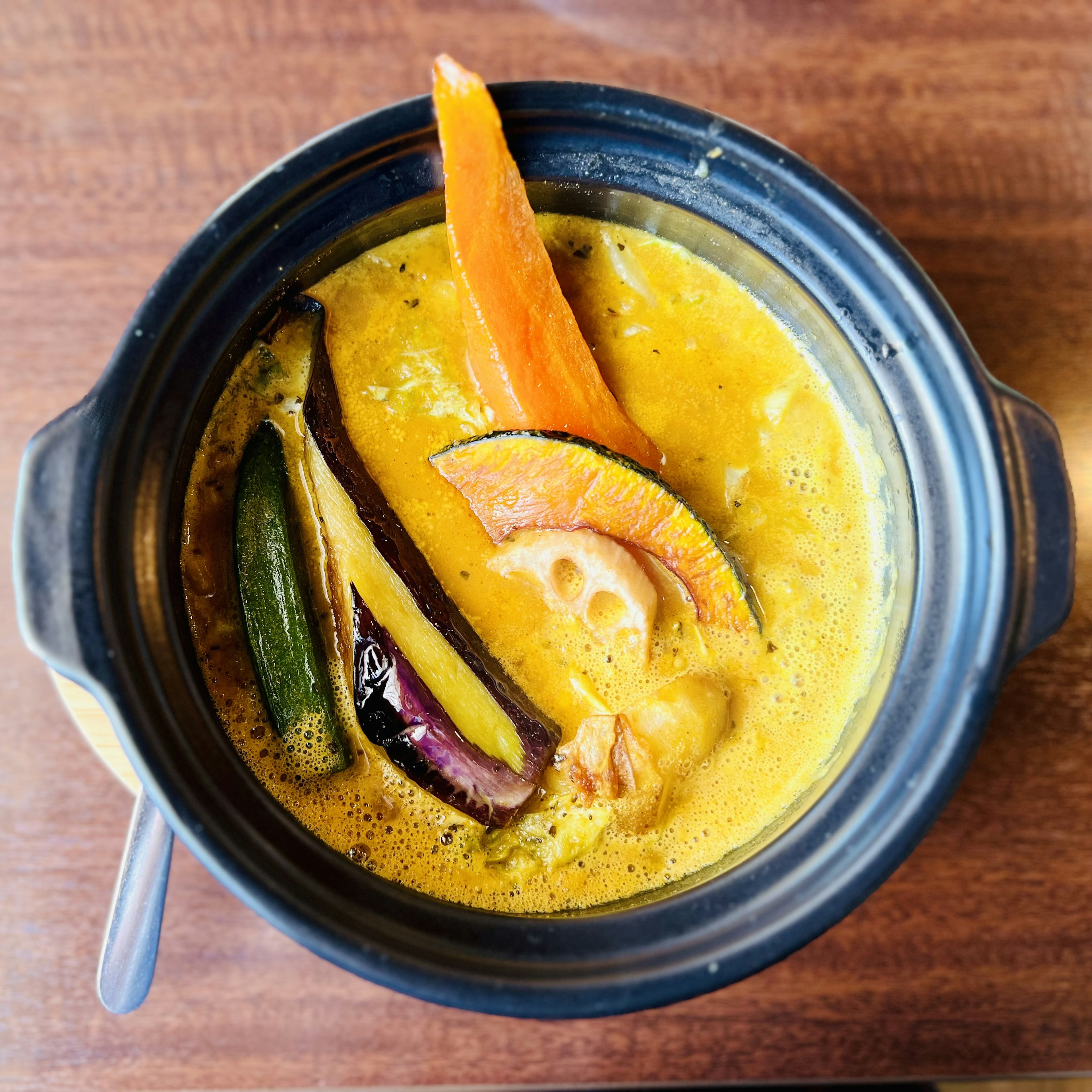 A curry-flavored soup with colorful vegetables and seafood