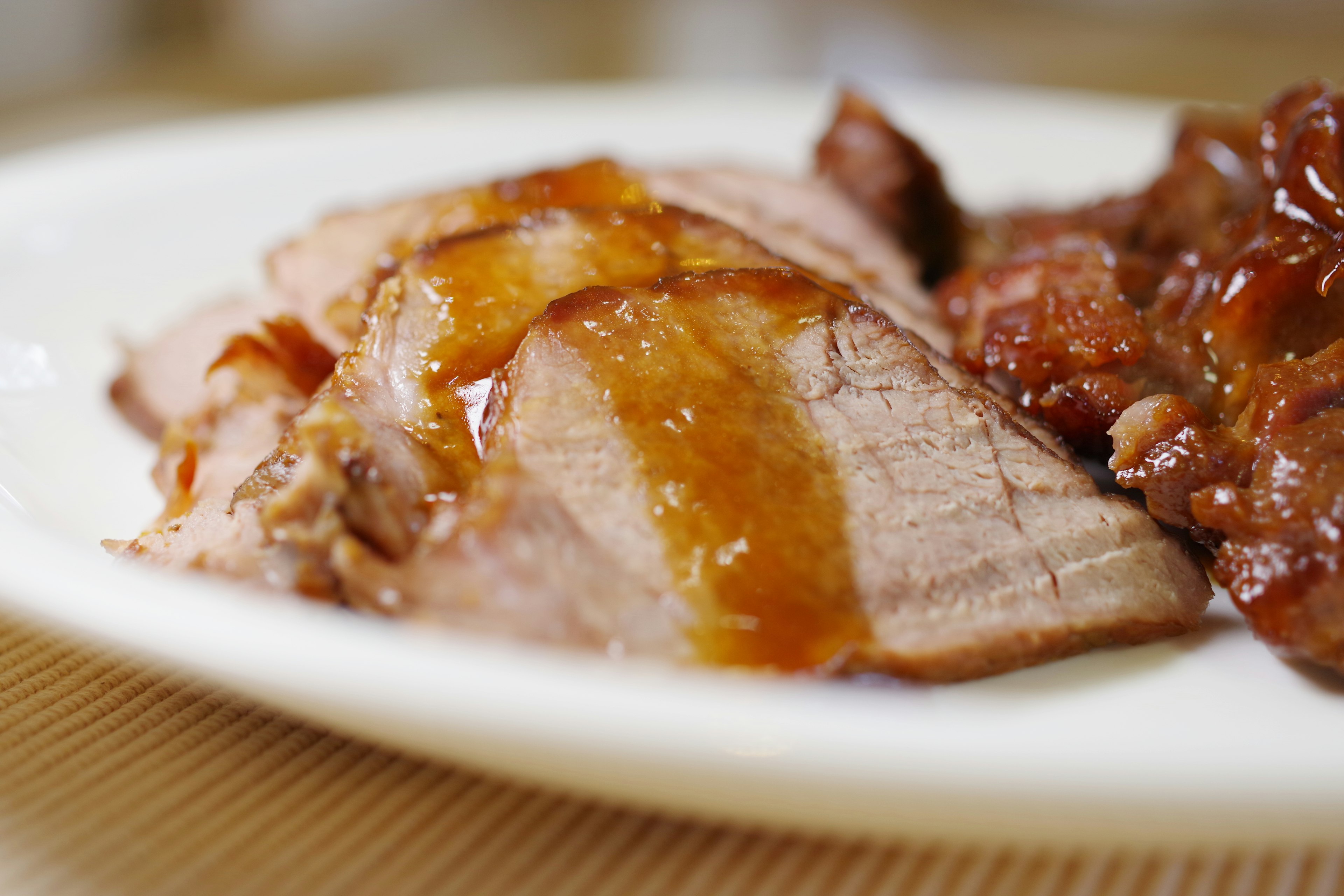 Carne en rodajas en un plato con una salsa dulce por encima