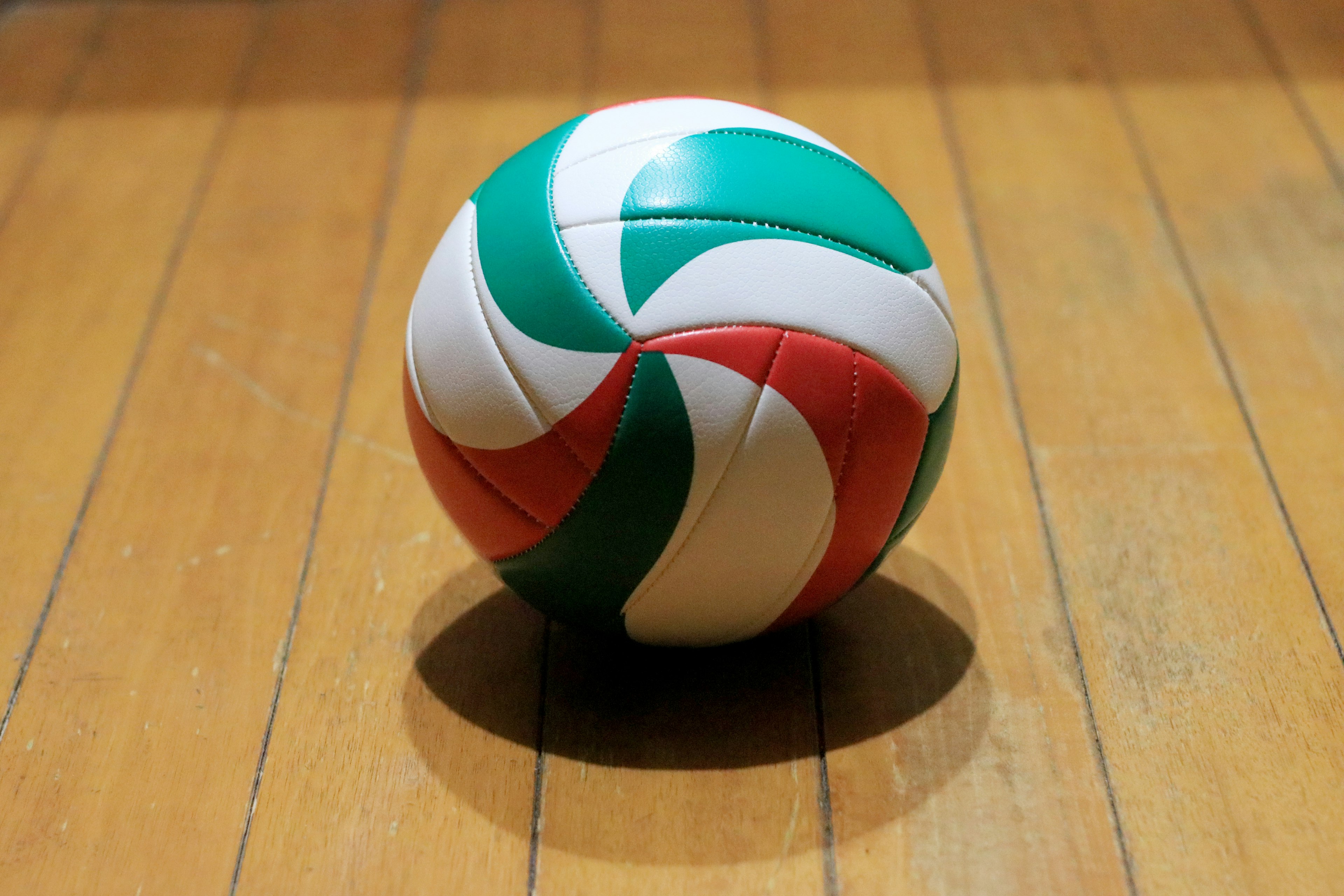 A colorful volleyball resting on a wooden floor