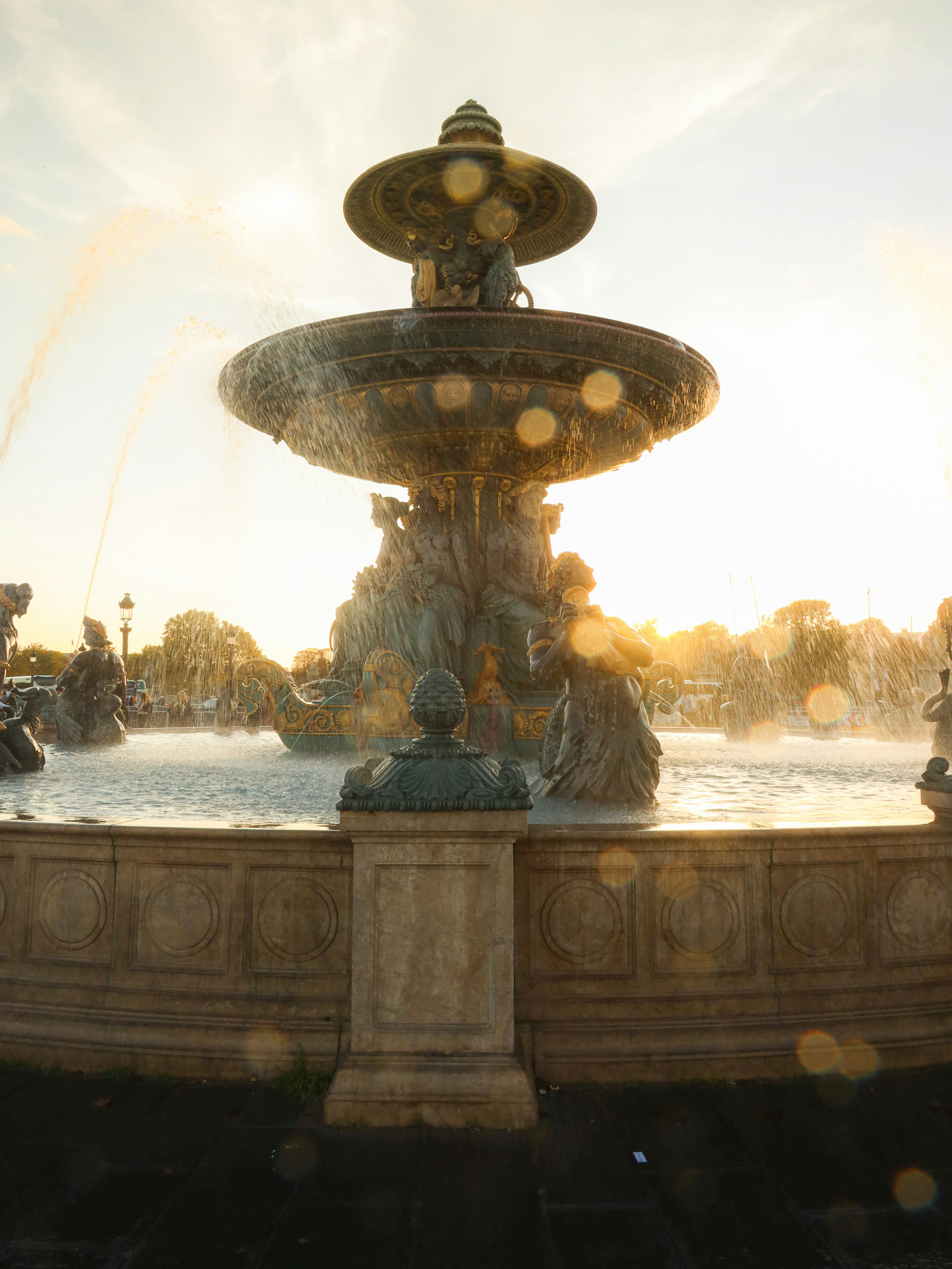 Schönes Foto eines Brunnens mit Sonnenuntergang, der die Wasserspritzer um ihn herum beleuchtet