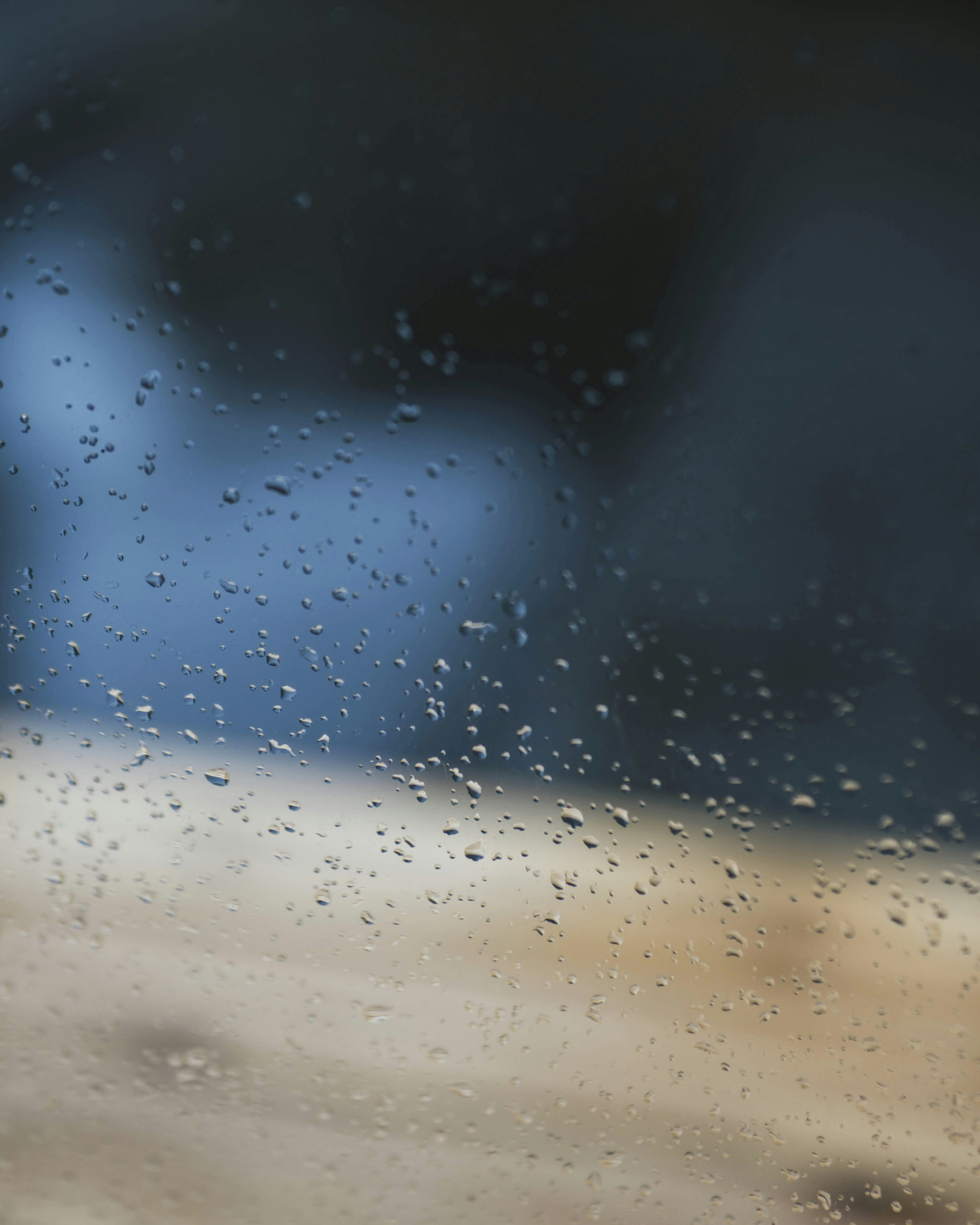 雨滴が付いた窓越しに見えるぼやけた風景