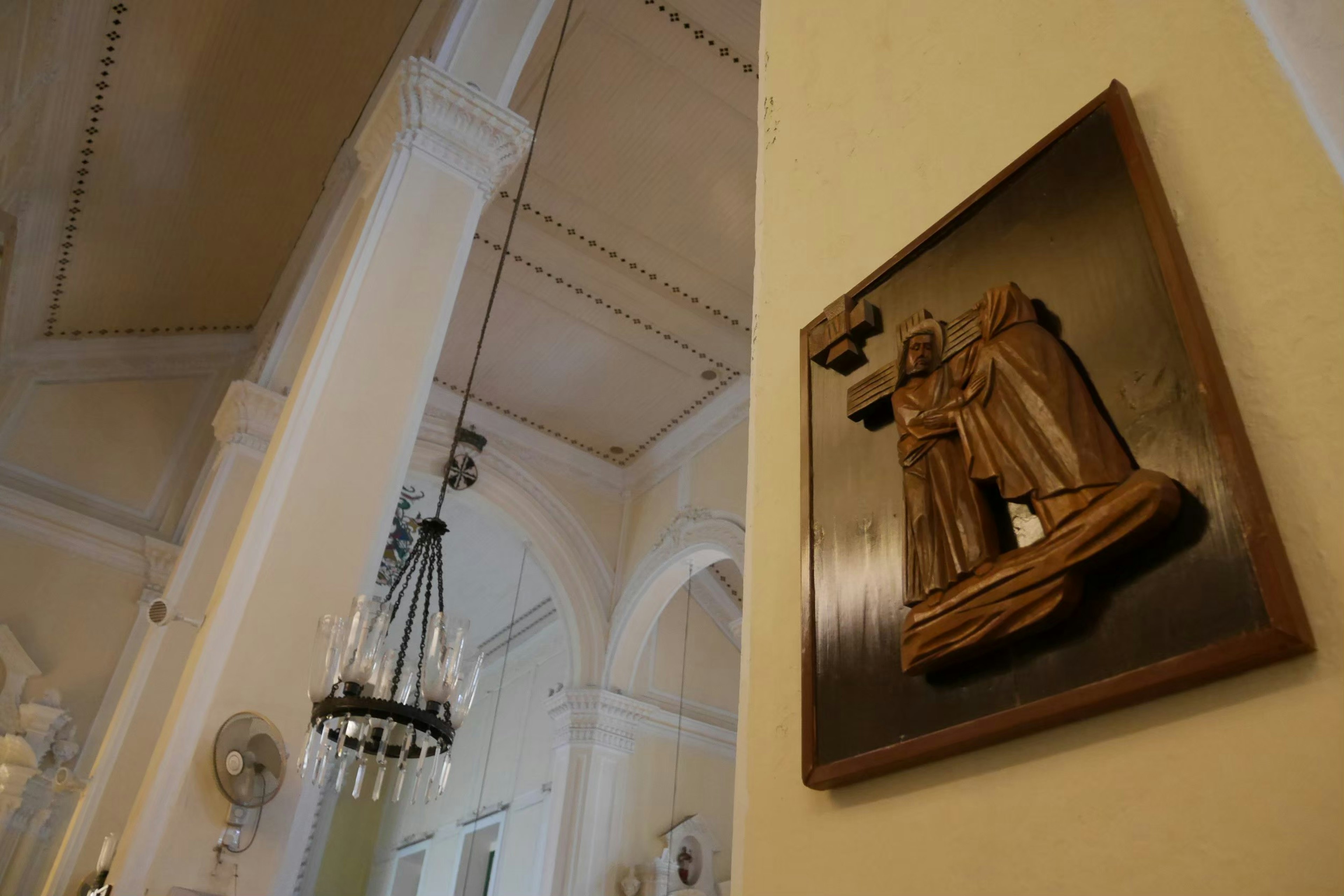 Interior gereja dengan patung kayu dan lampu gantung