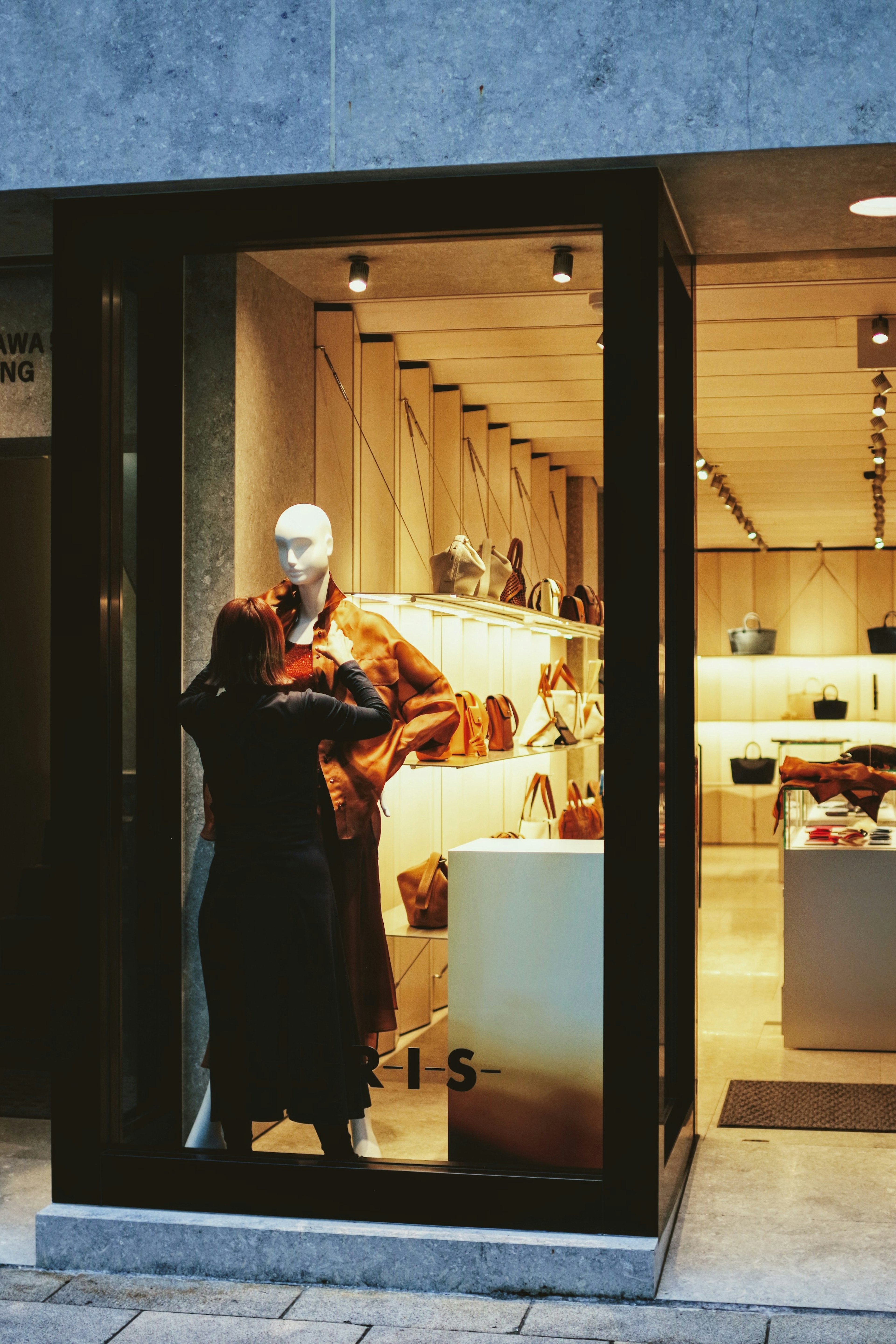 Eine Frau steht vor einem Schaufenster mit einem Mannequin, das stilvolle Kleidung trägt