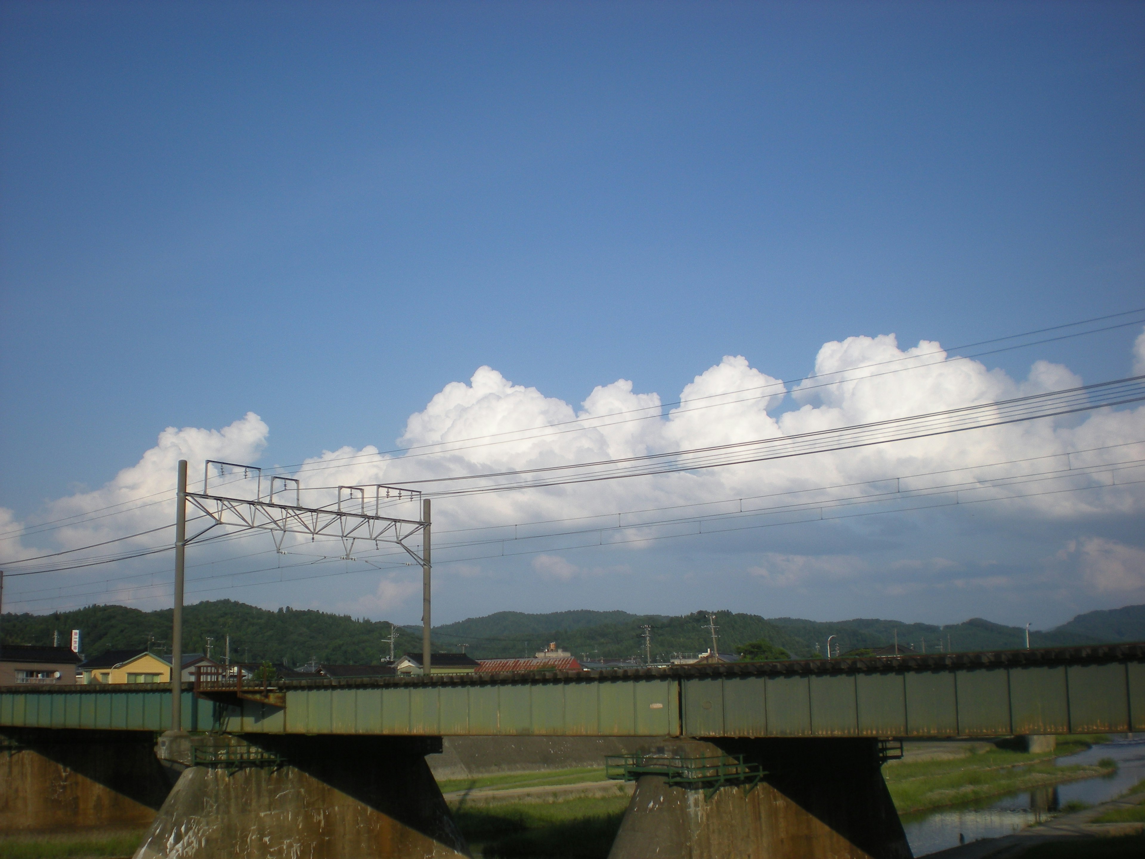 青空の下に広がる白い雲と緑の橋