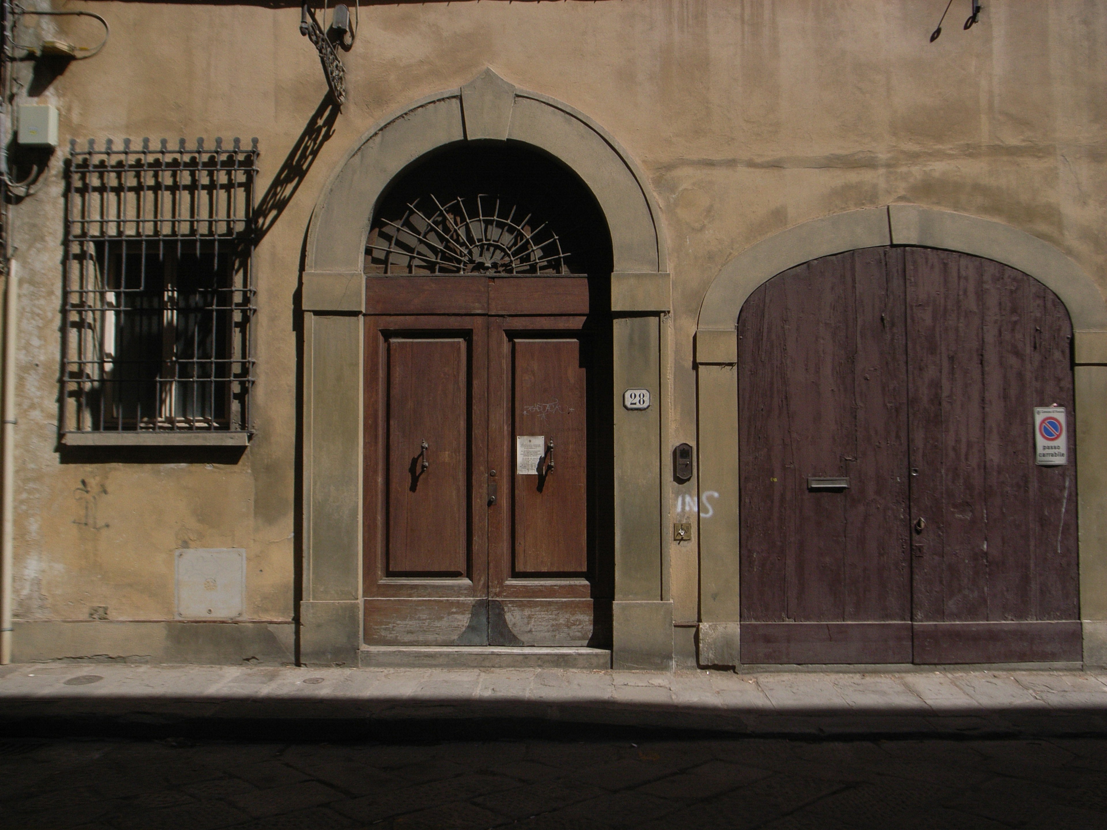 Exterior of an old building featuring wooden doors and an arched window