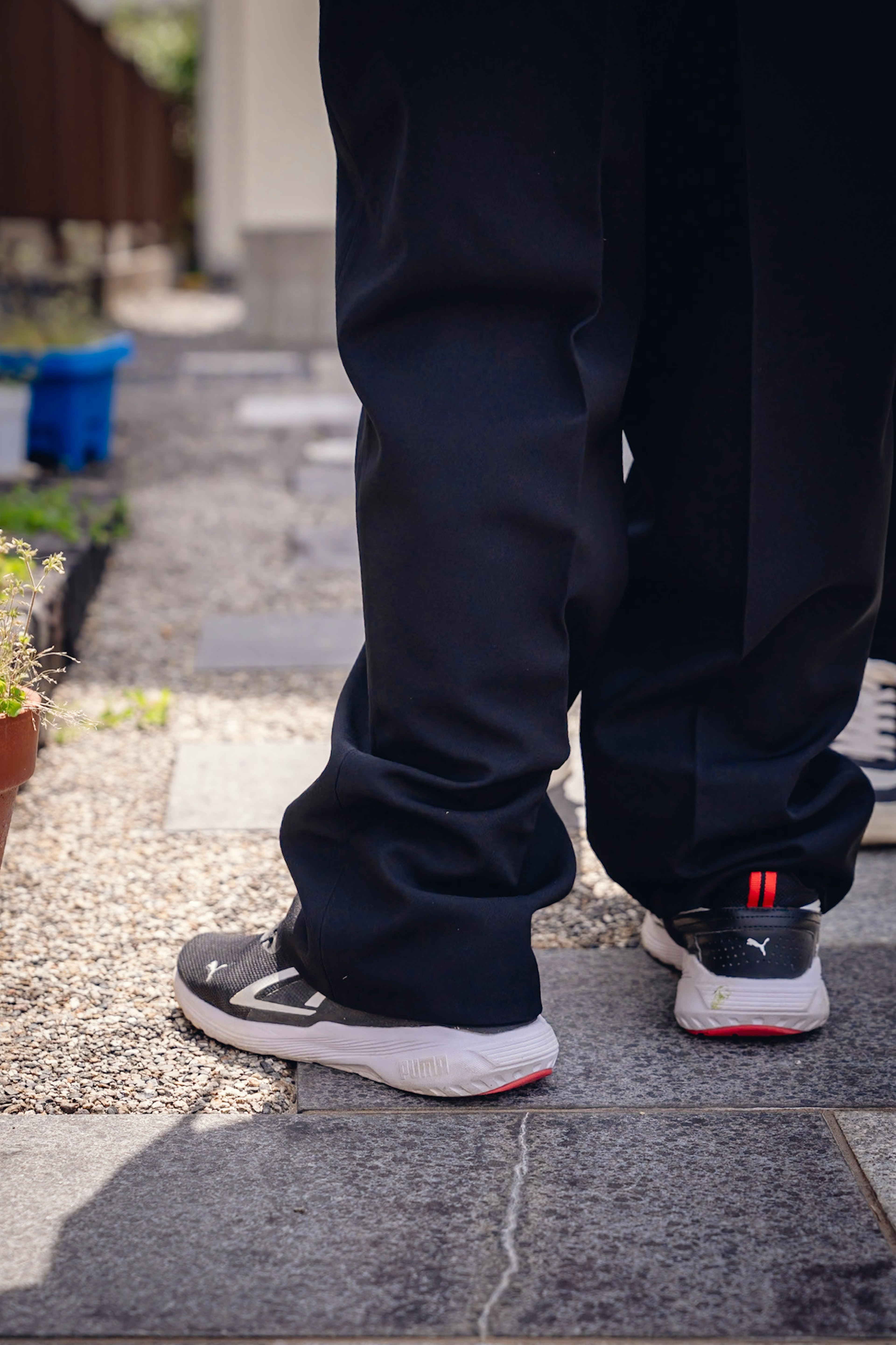 Persona con pantaloni neri e sneakers di spalle