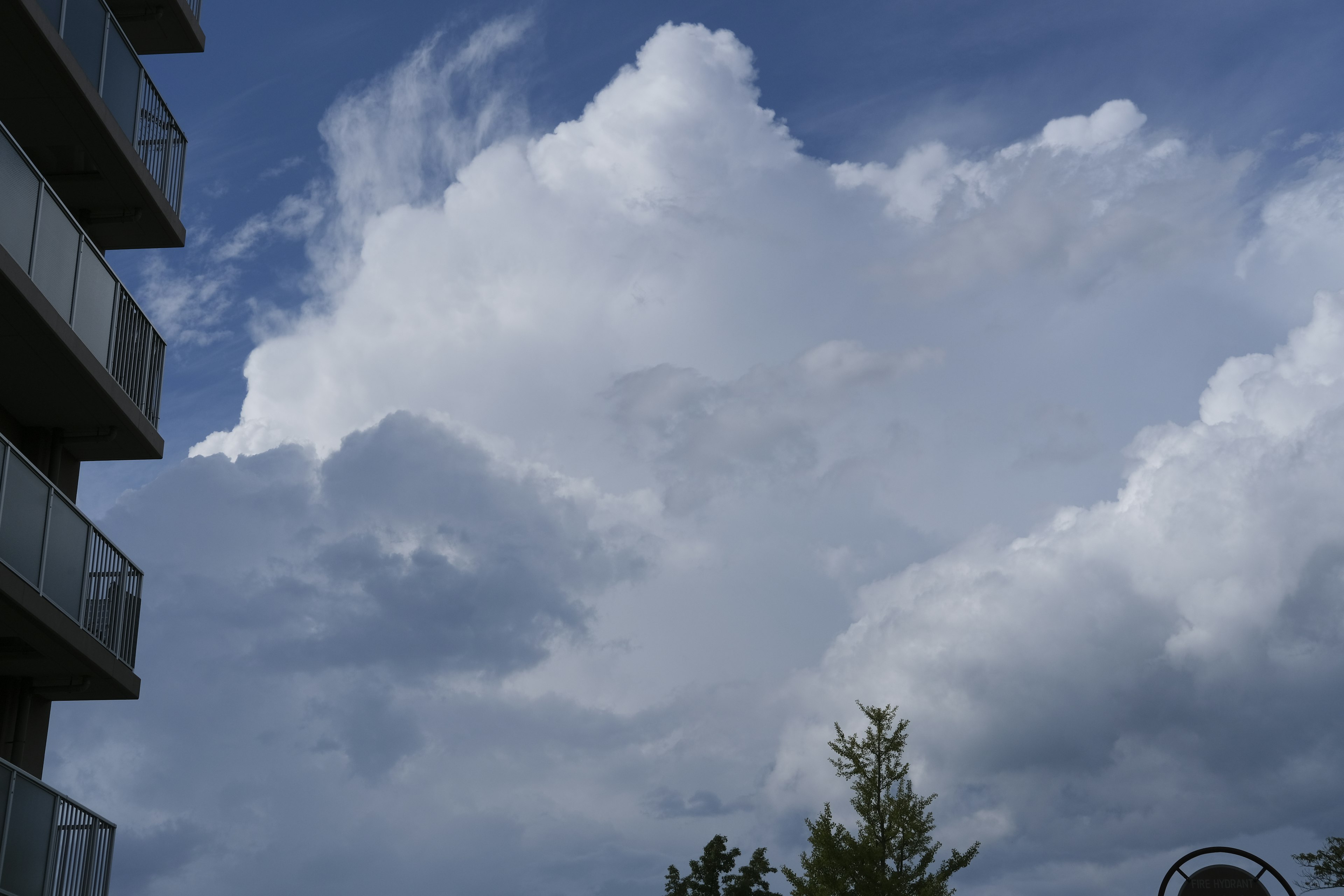 Fluffy white clouds in a blue sky with part of a high-rise building