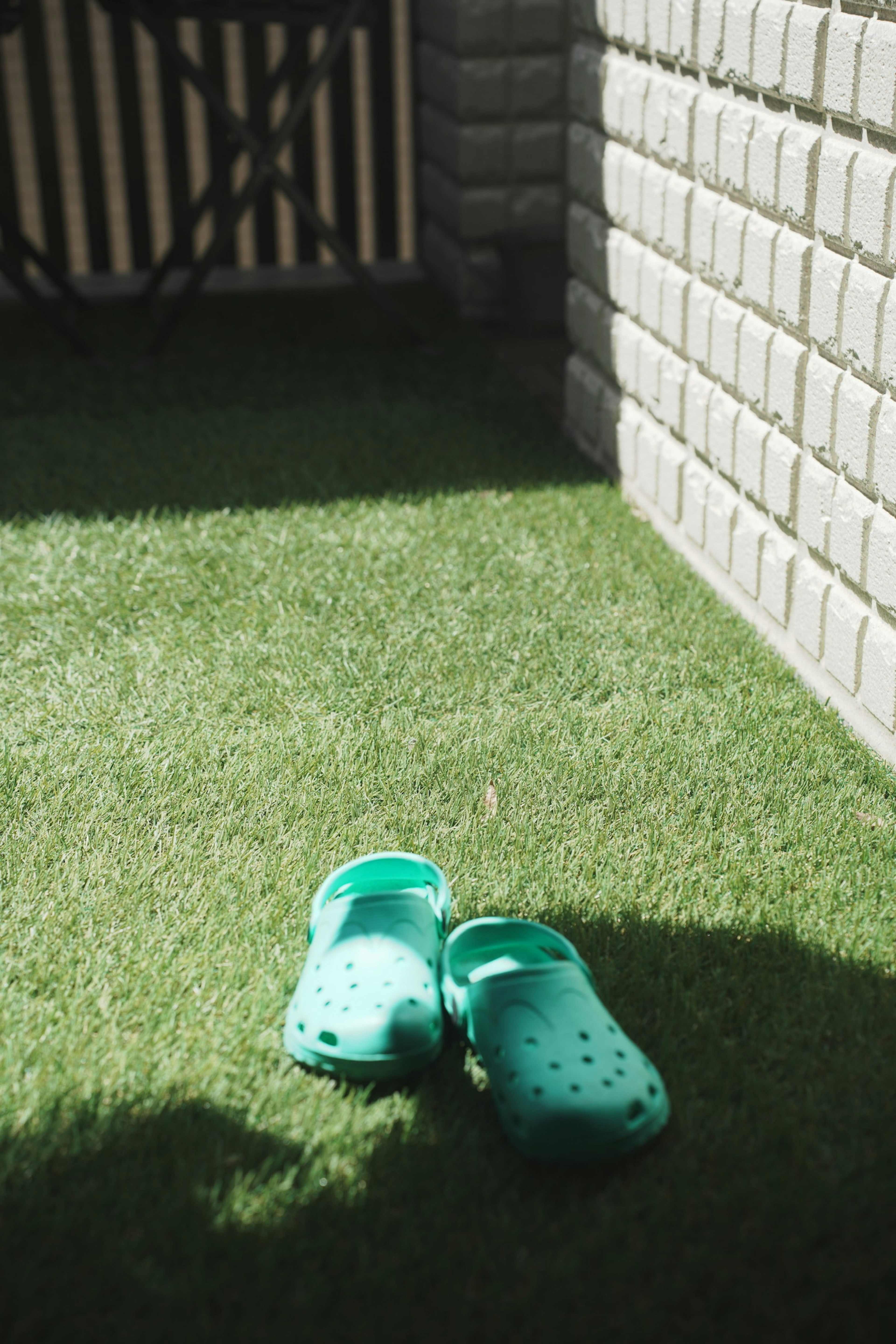 Green crocs placed on artificial grass