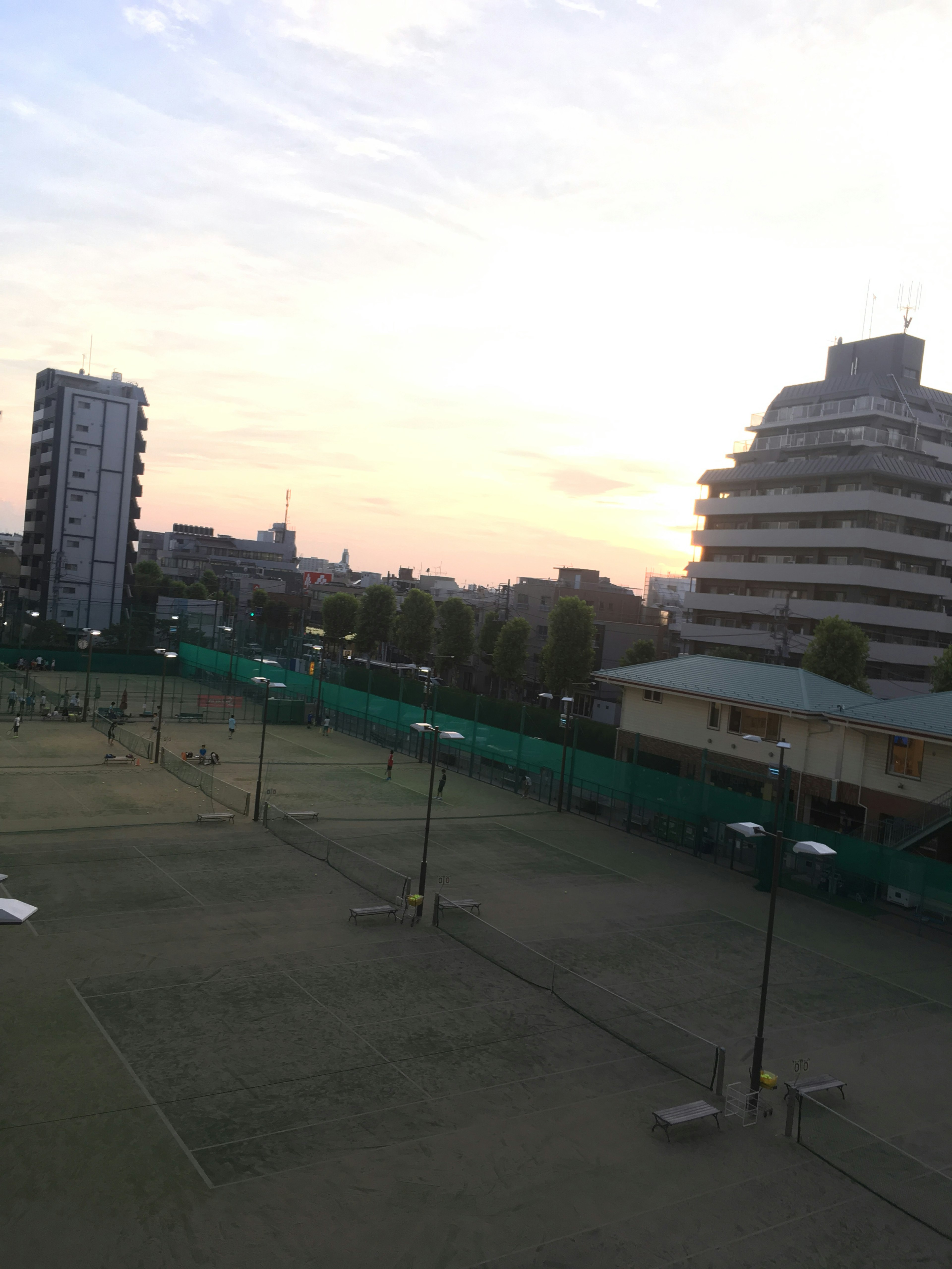 สนามเทนนิสพร้อมท้องฟ้ายามพระอาทิตย์ตกและทิวทัศน์เมือง