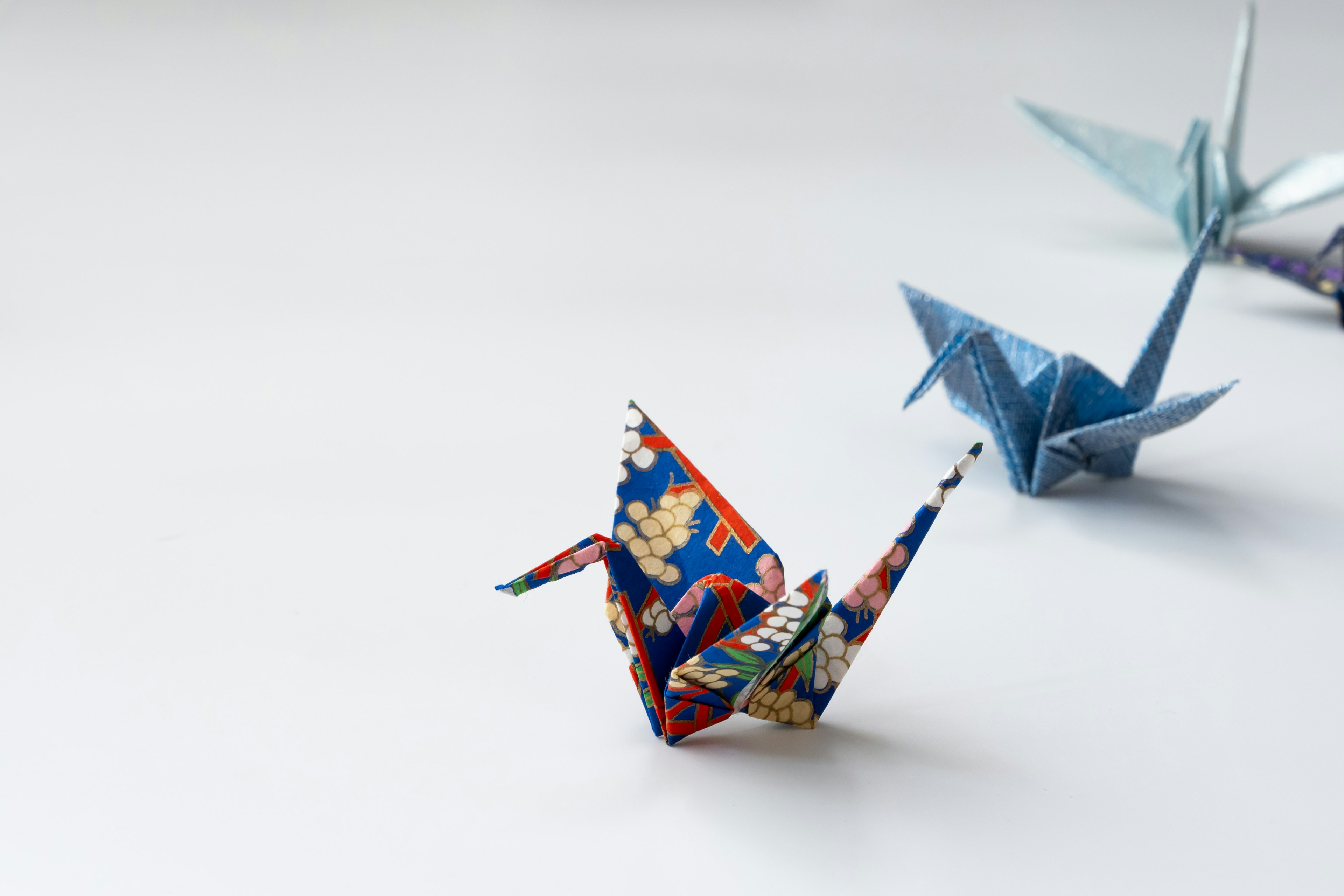 Colorful origami cranes arranged on a simple background