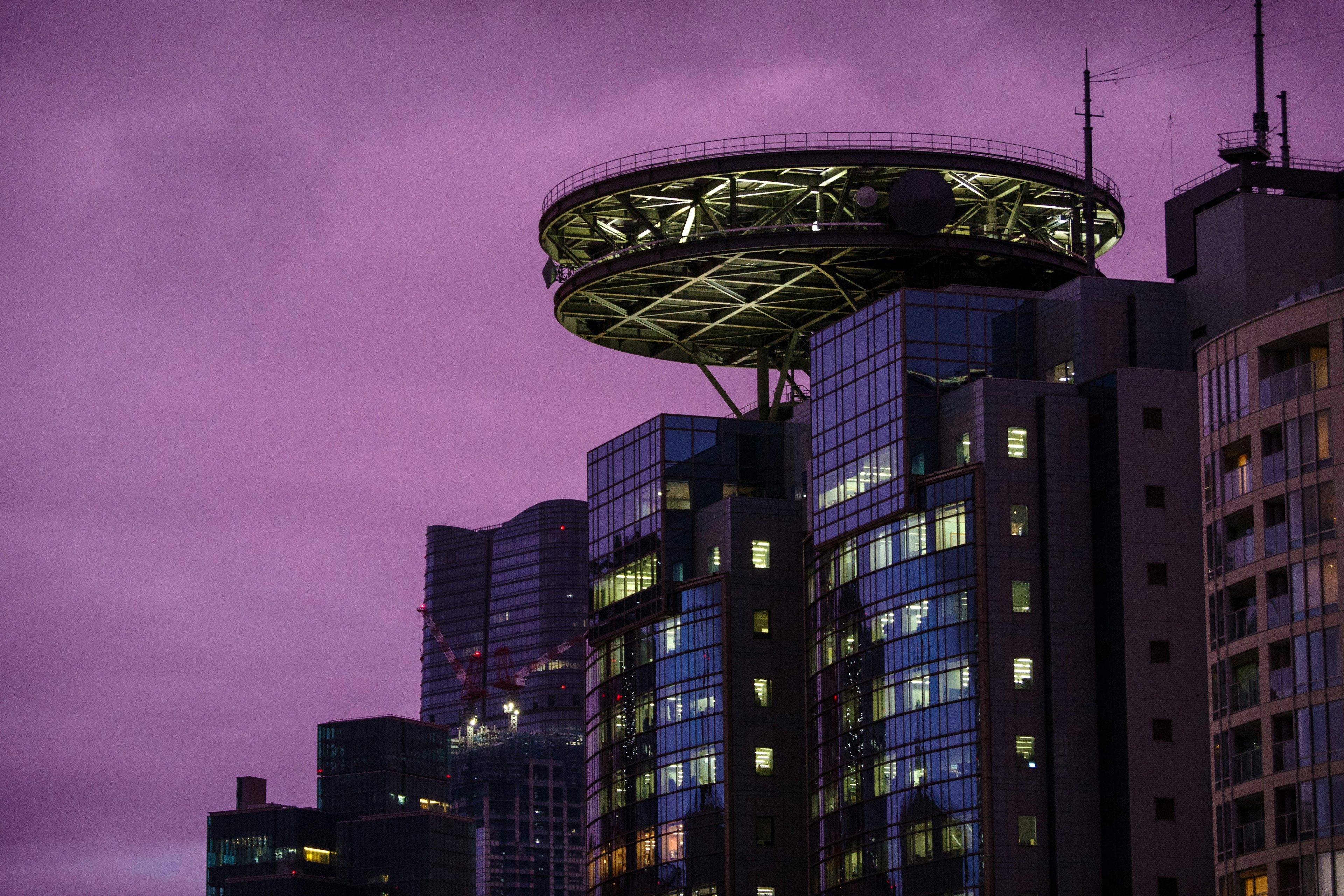 Modernes Gebäude mit kreisförmiger Struktur oben unter einem lila Himmel