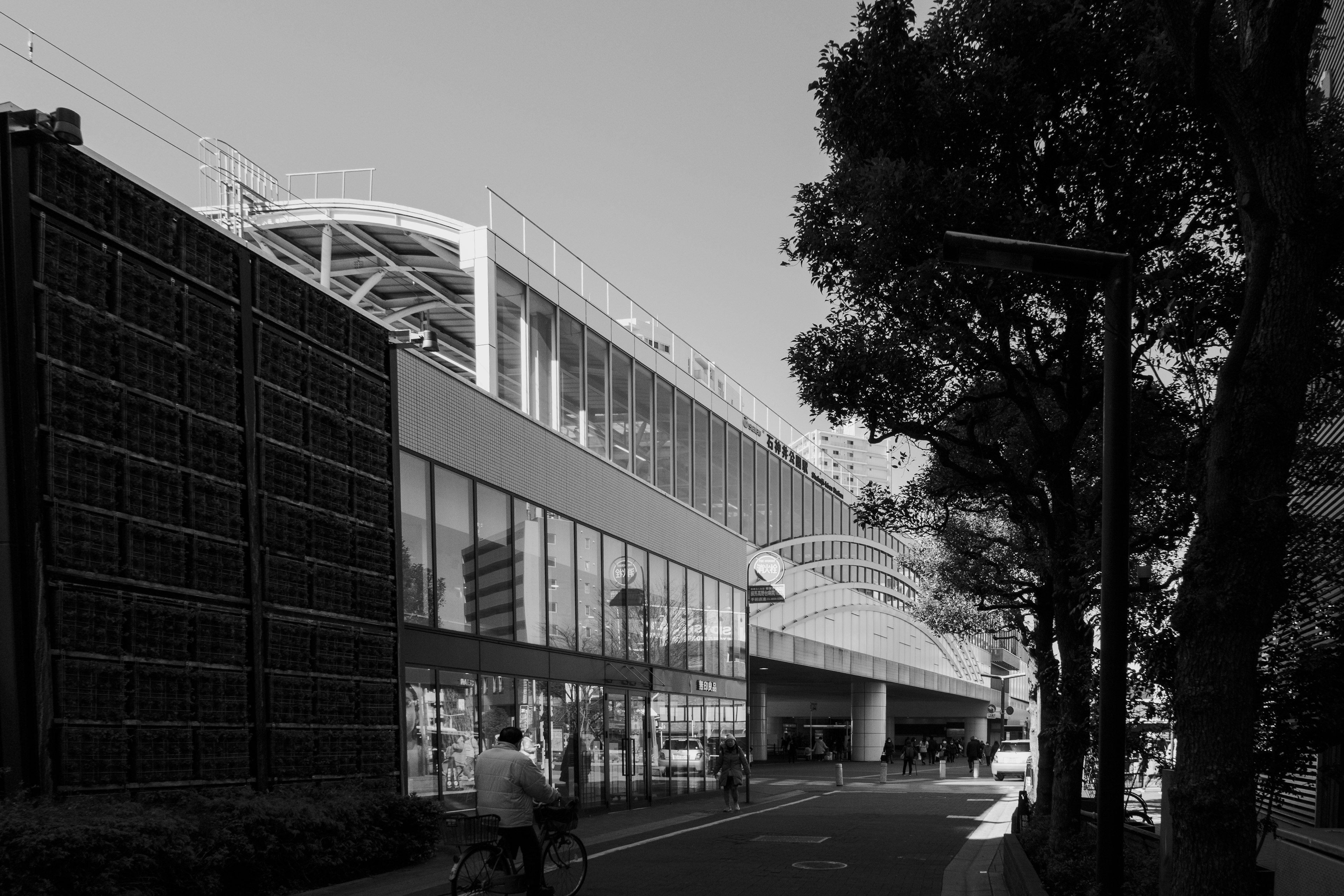 Black and white cityscape featuring a train station and surrounding buildings with a bicycle on the road