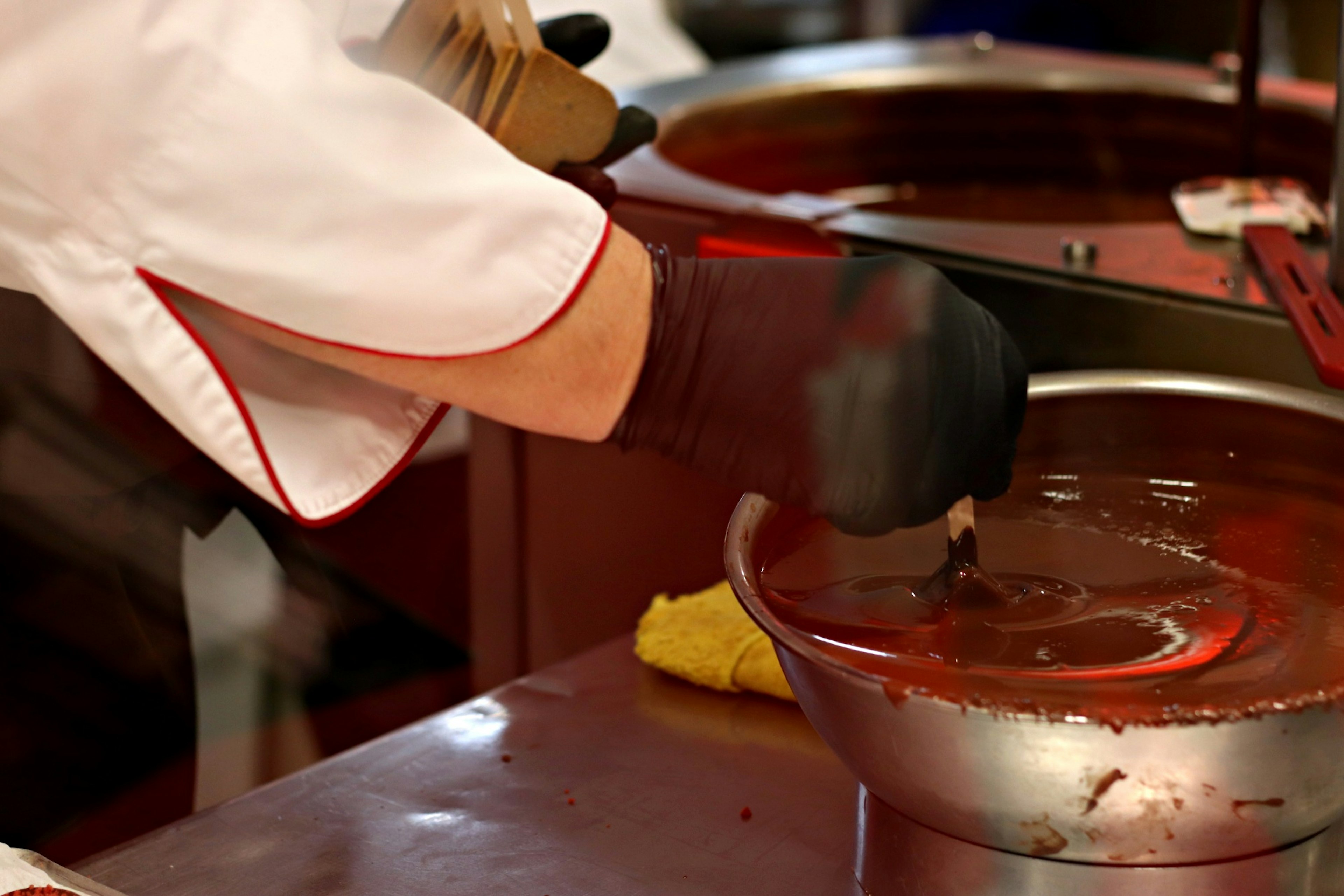 Una mano di chef che intinge nel cioccolato fuso in una cucina