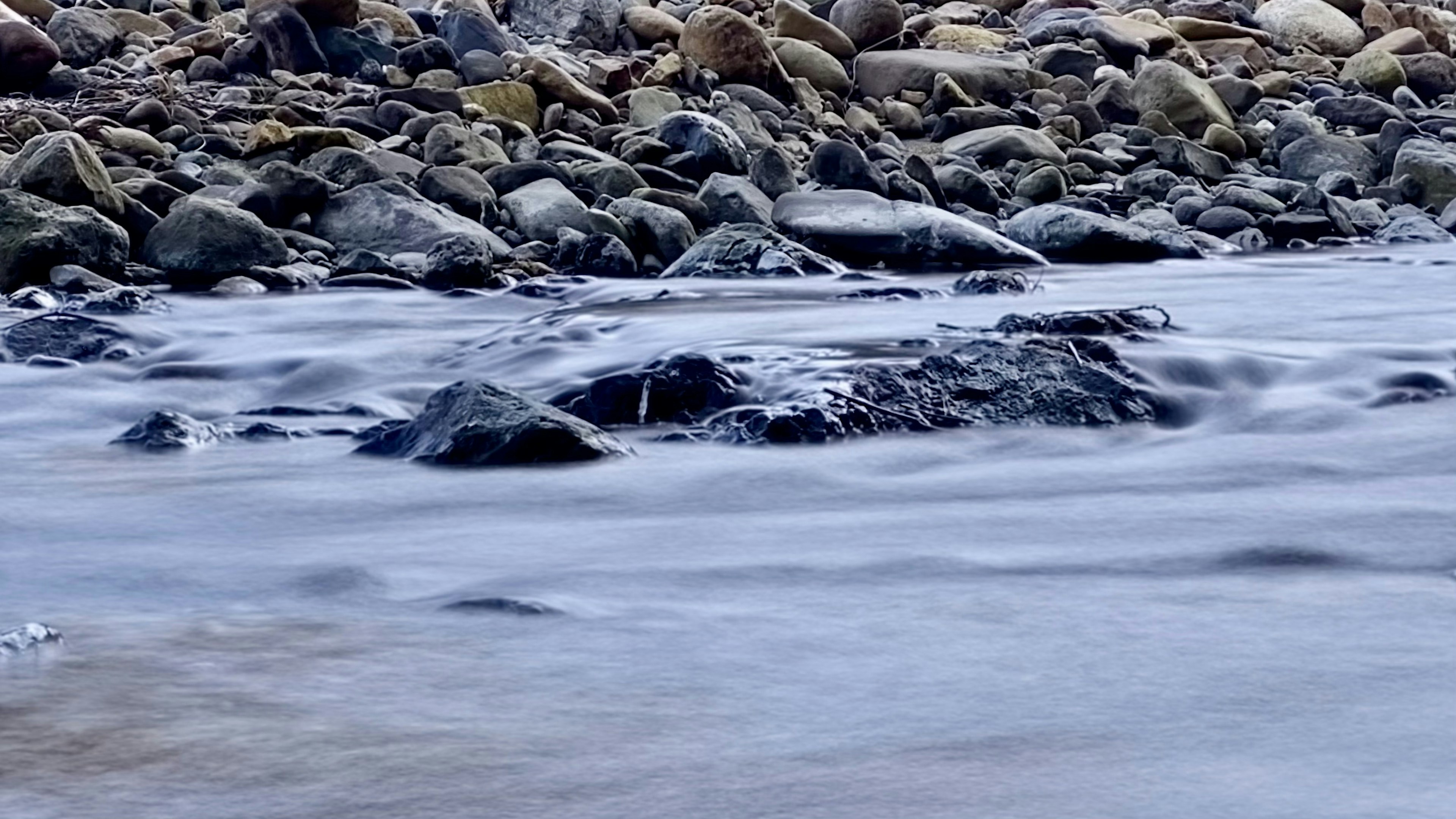 Fließendes Wasser über Steine in einer Strandszene