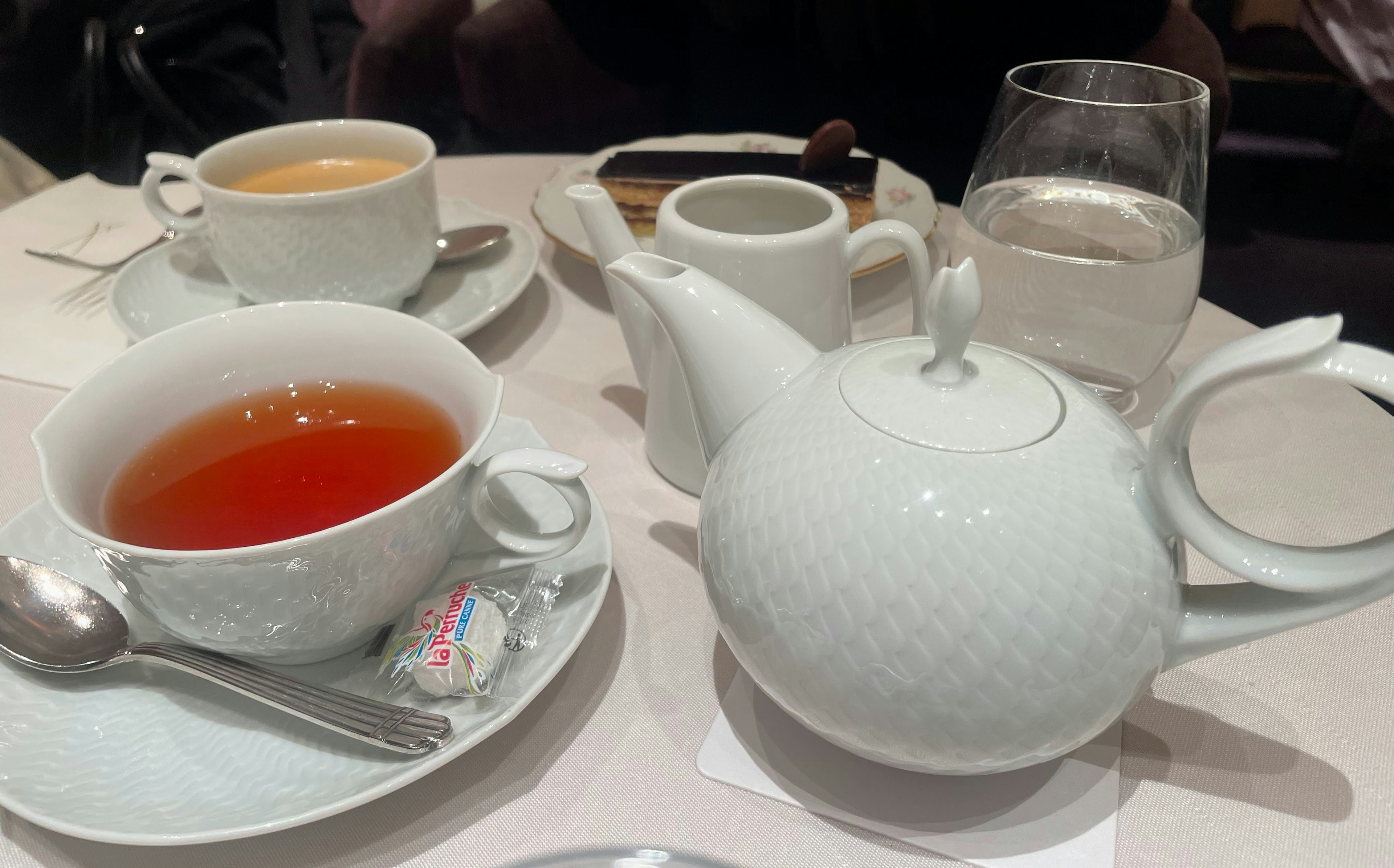 Table setting with a white teapot and a cup of black tea