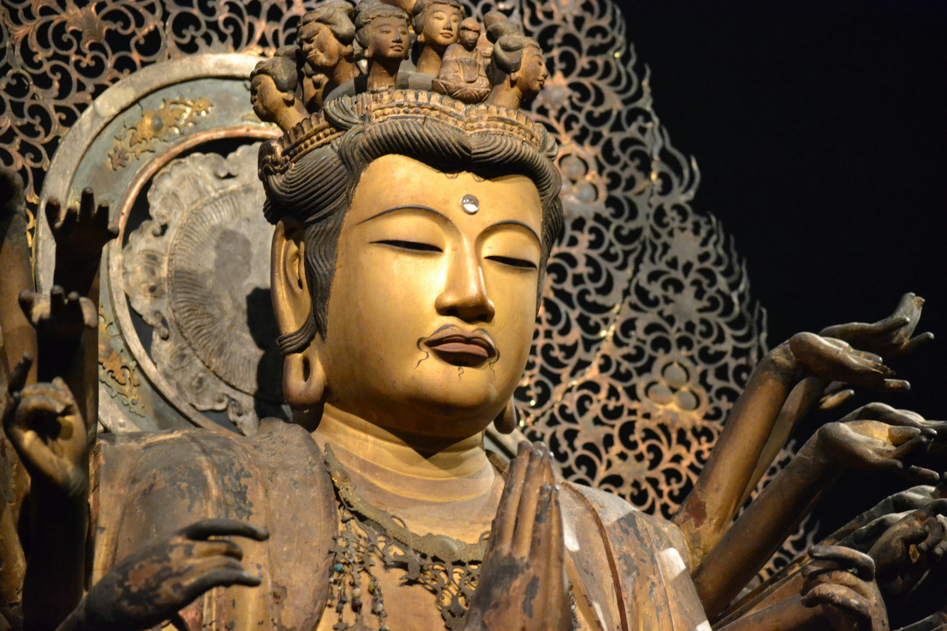 Close-up of a multi-armed statue depicting a serene face and intricate hair