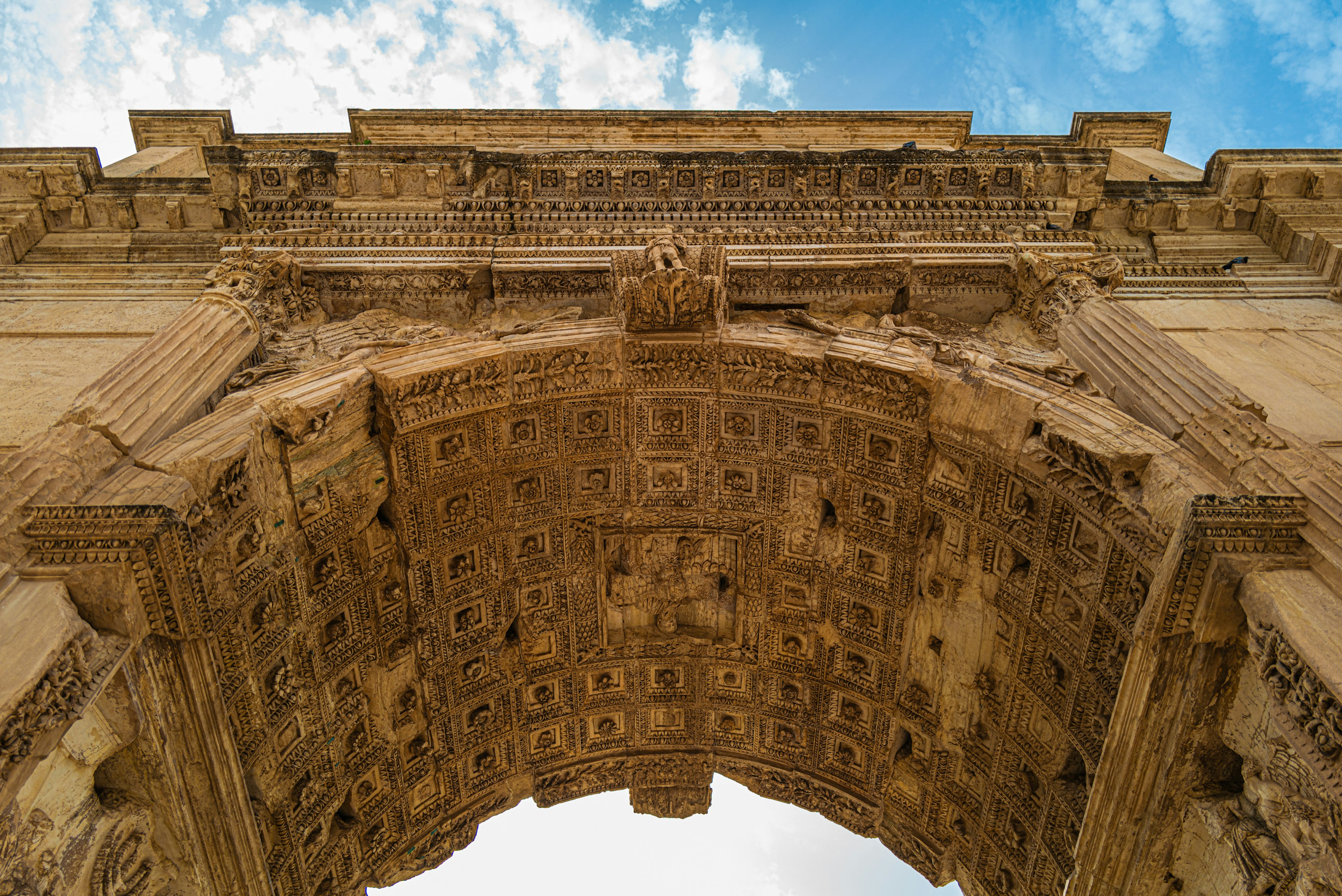 Détails des sculptures d'une arche ancienne sous un ciel bleu