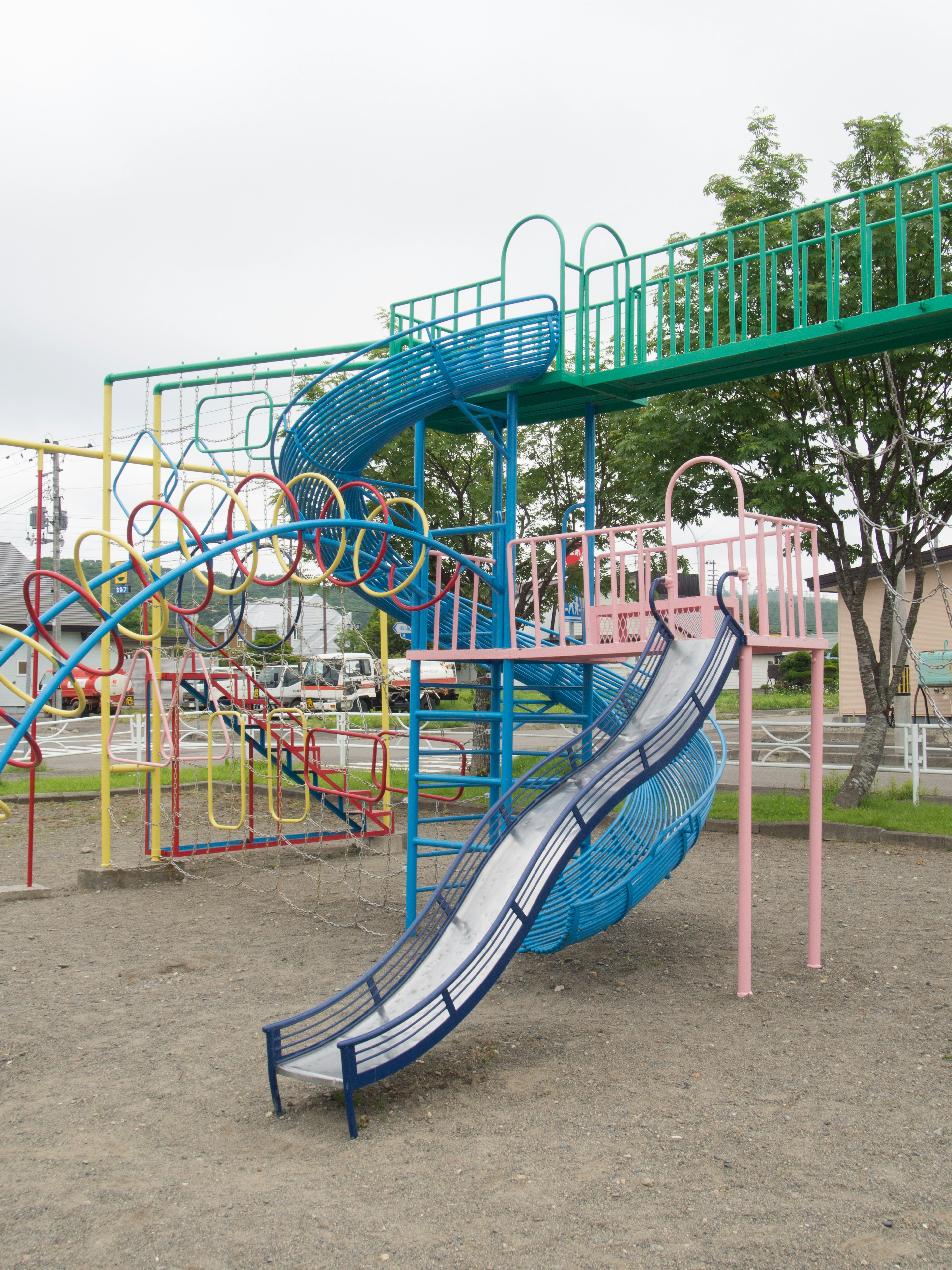 Parque infantil con tobogán azul y estructura de escalada verde