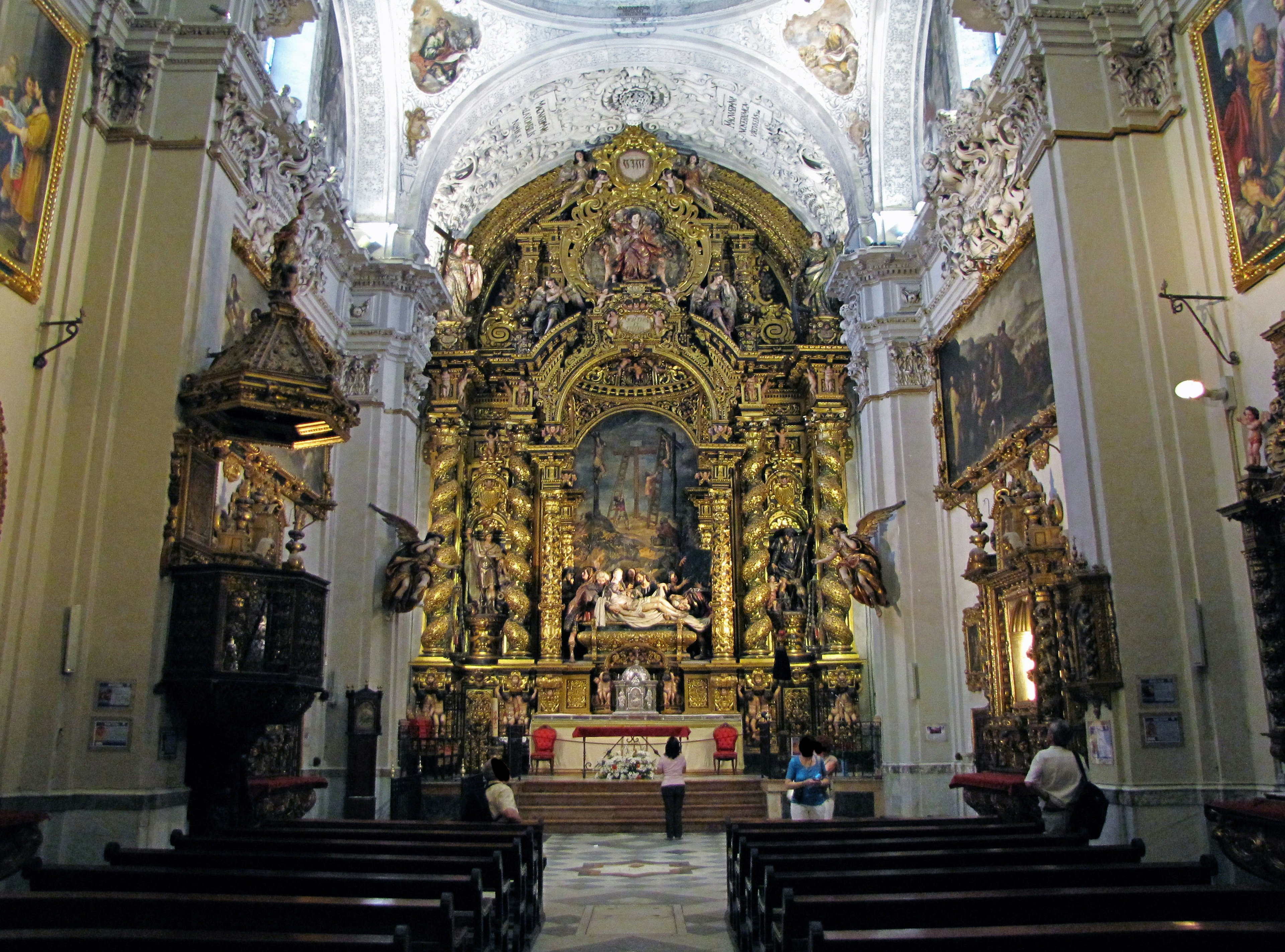 Interior gereja yang megah dengan altar emas dan banyak patung, suasana tenang