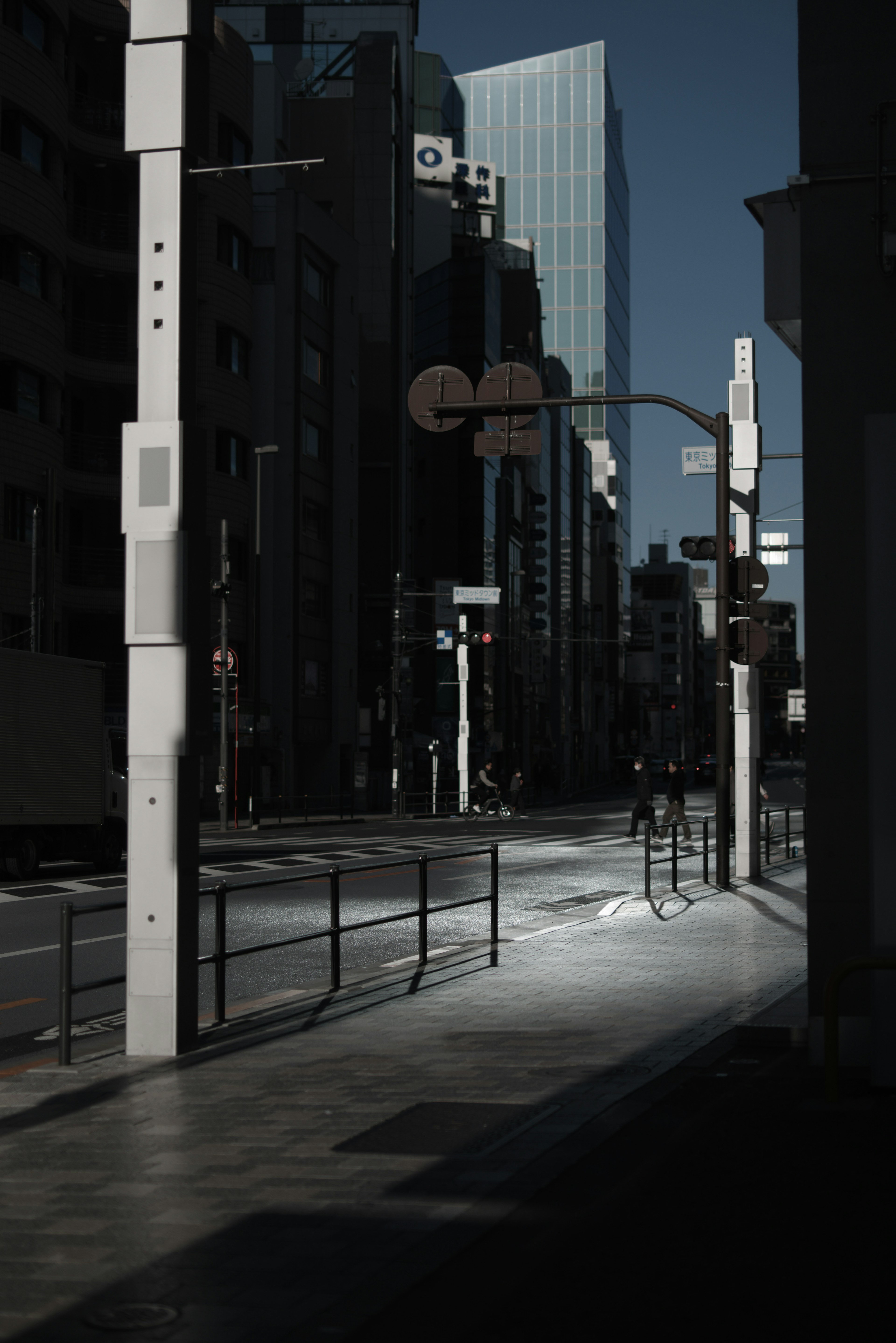 A shadowy street scene featuring a lone figure and a tall building in the background