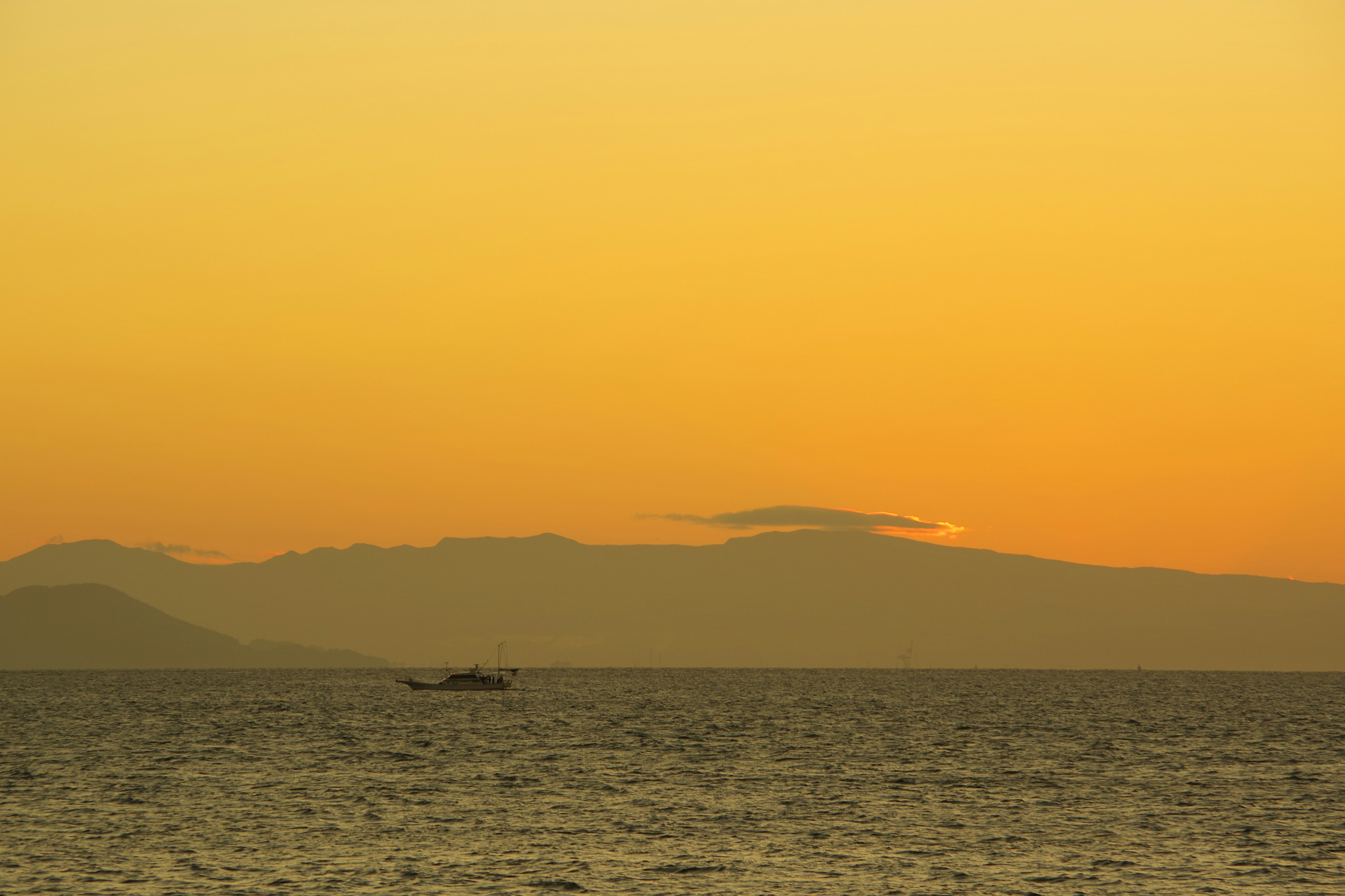 Senja di atas laut dengan siluet gunung