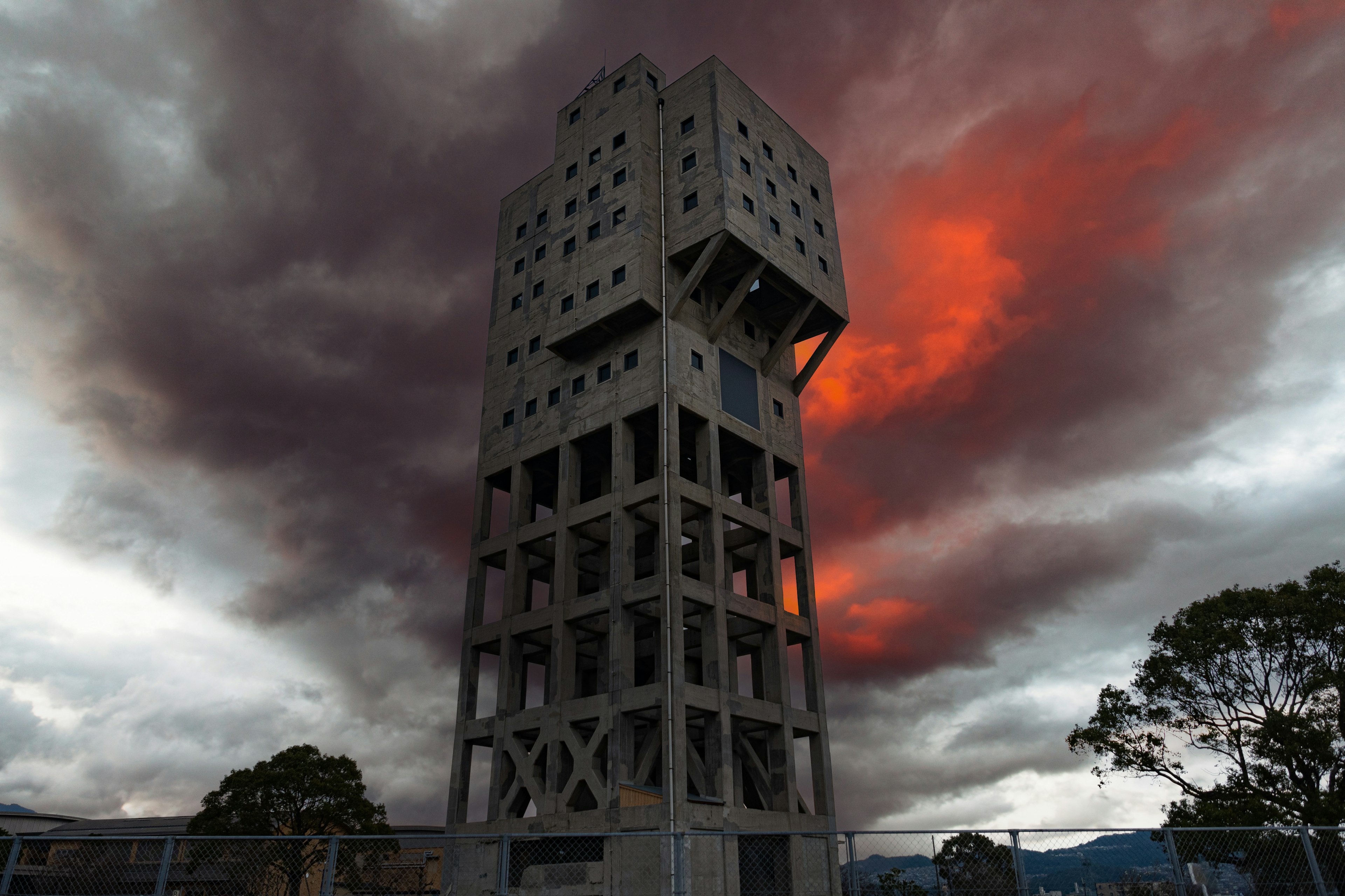 Eine hohe Struktur vor einem dramatischen Himmel mit dunklen Wolken und roten Farbtönen