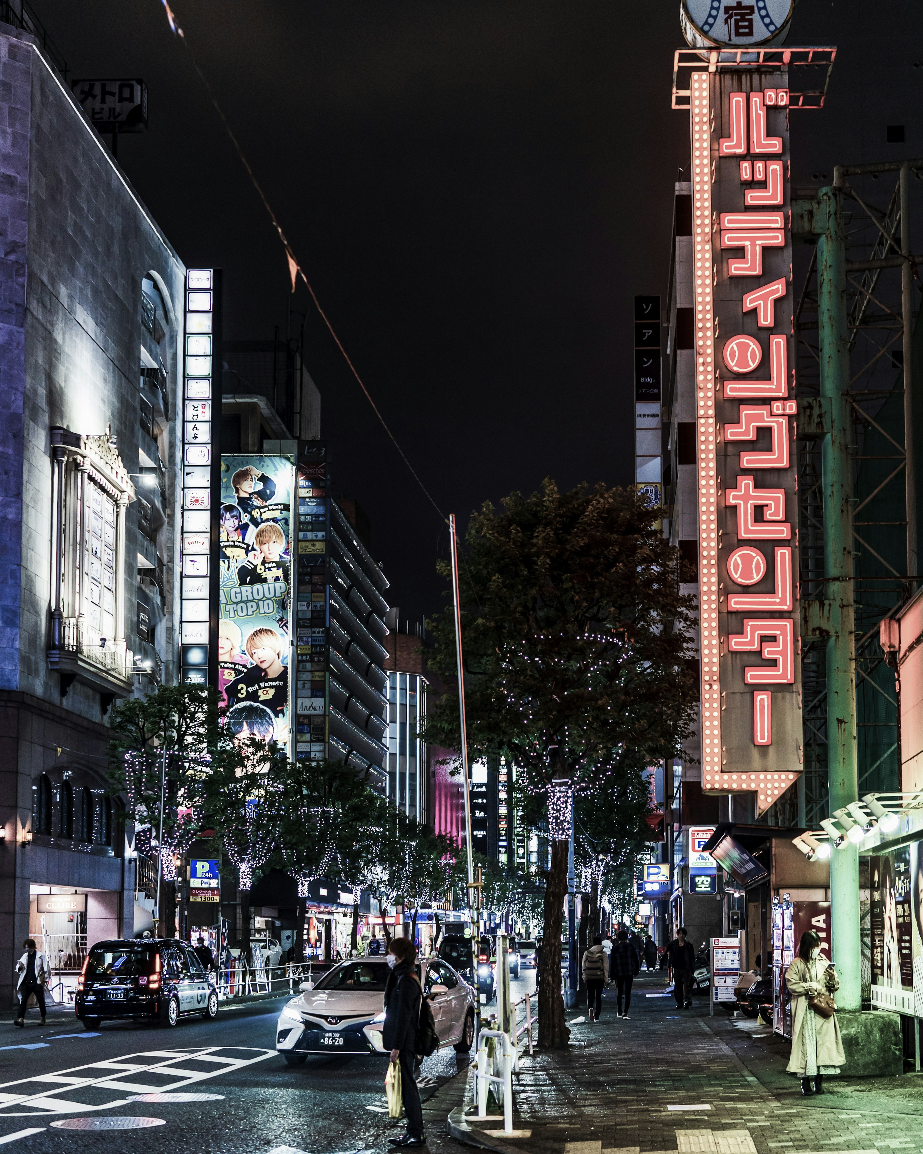 Nighttime urban scene featuring neon signs and pedestrians