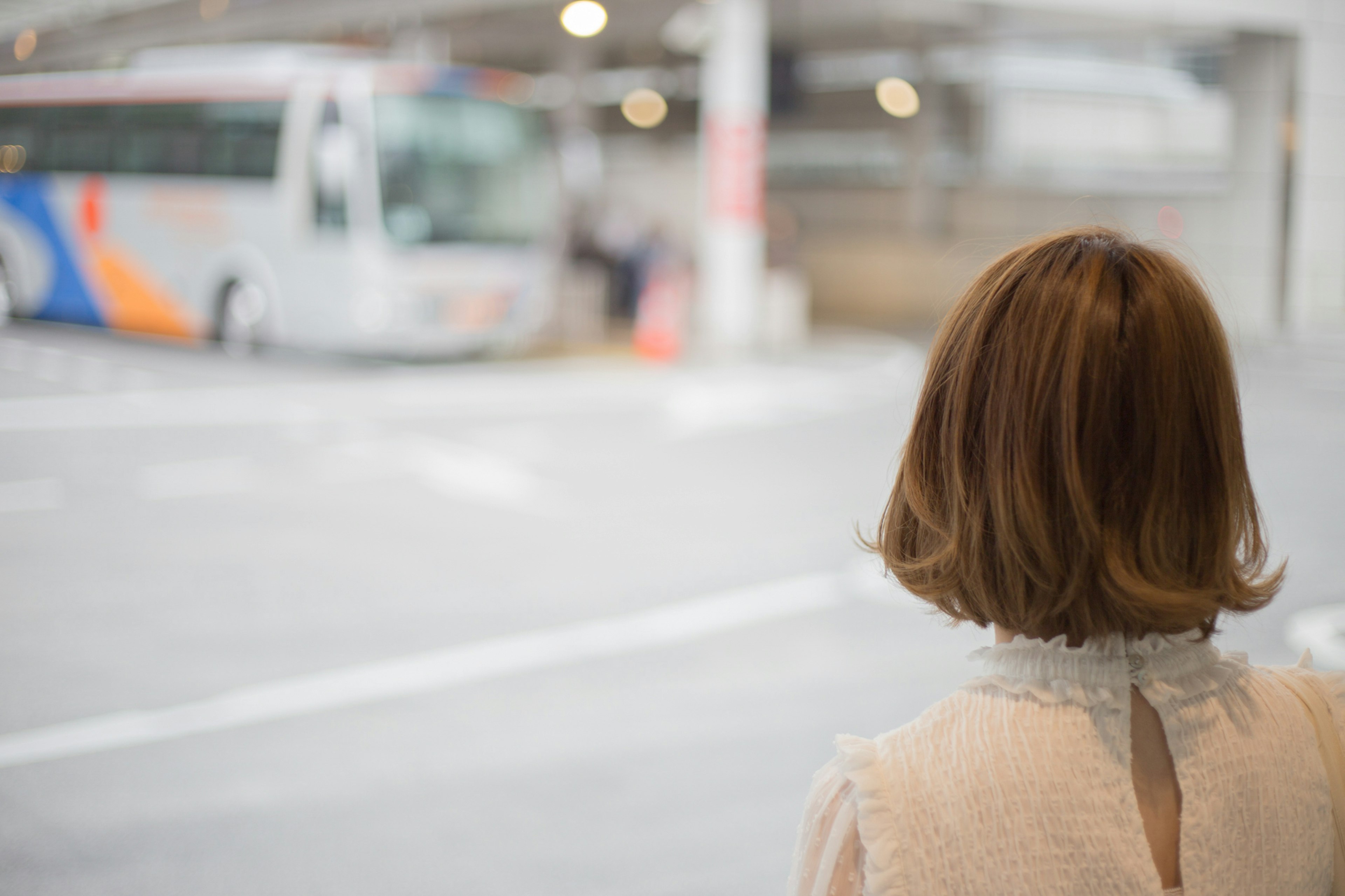 Mujer esperando un autobús con un autobús borroso al fondo