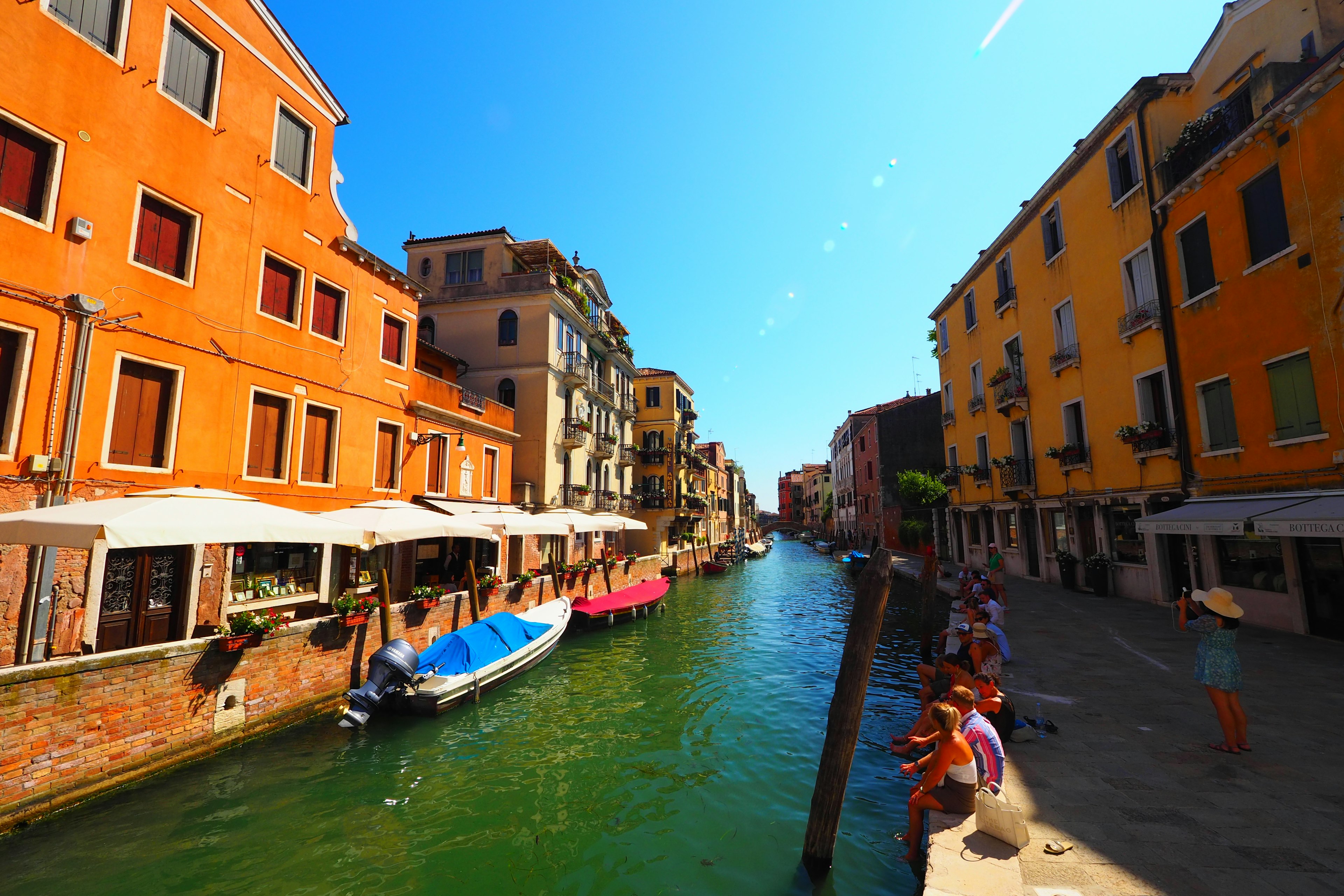 A vibrant view of colorful buildings along a canal in Venice under a bright blue sky