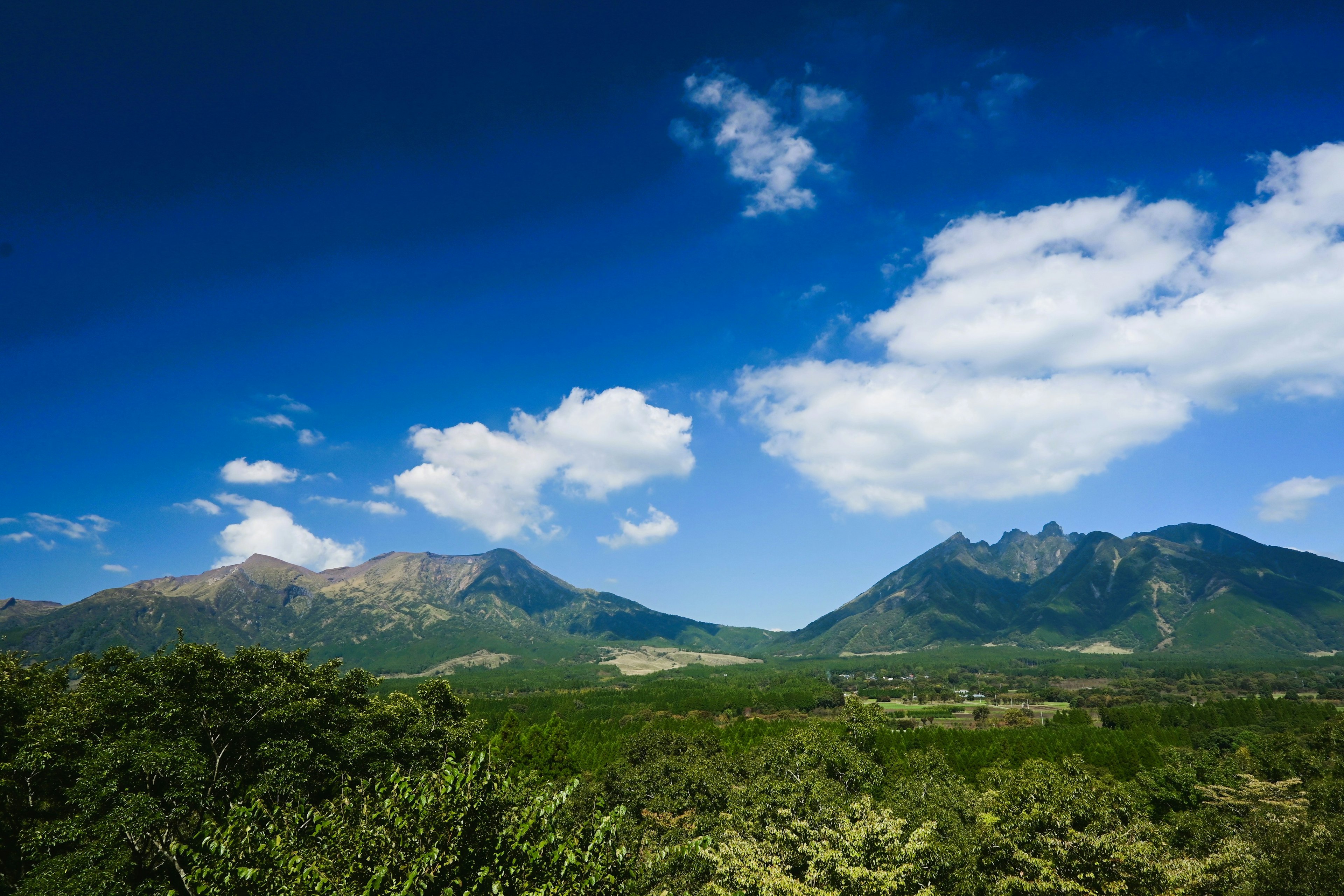 青空と白い雲に囲まれた山々の風景