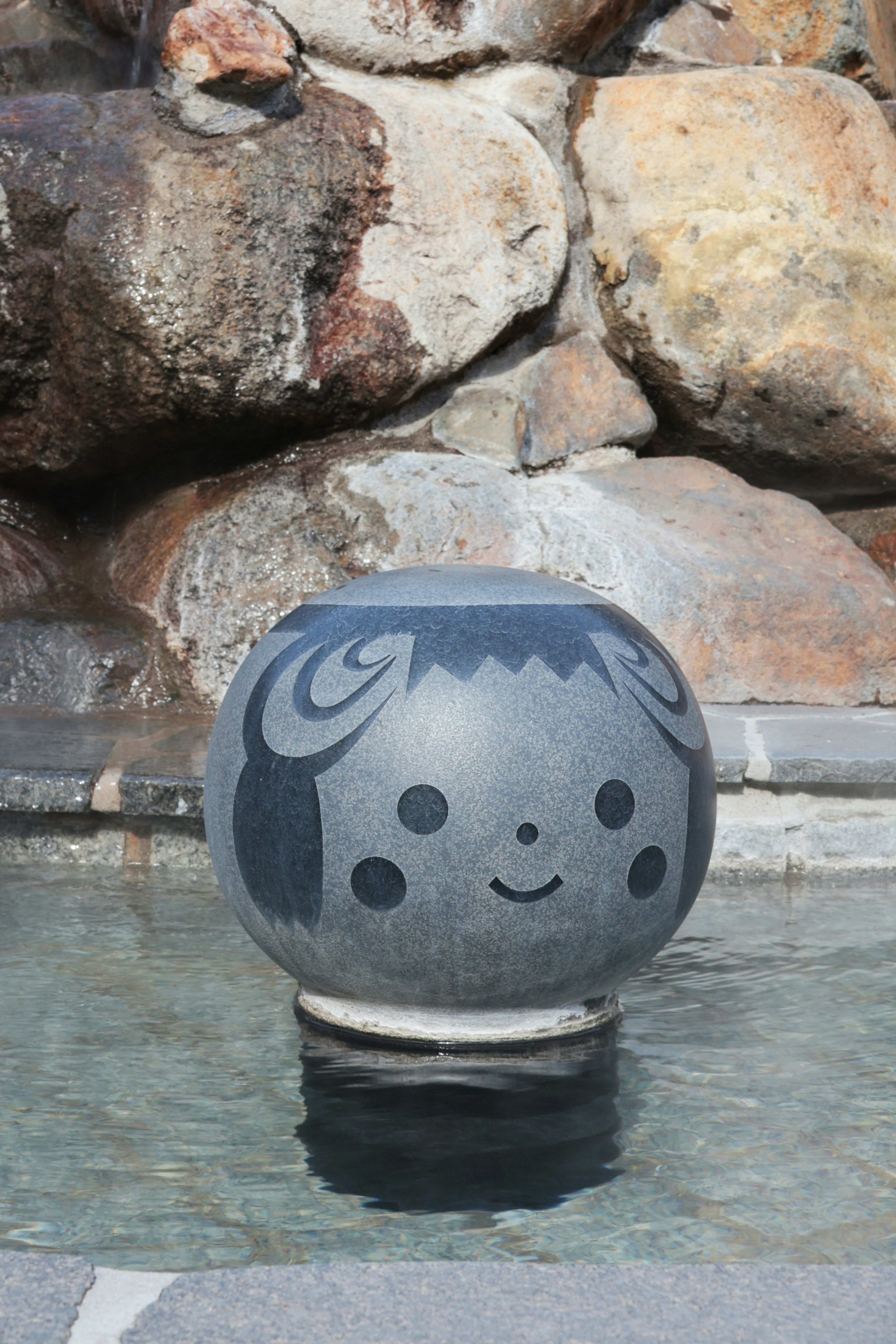 Cute stone sculpture with a smiling face floating in water