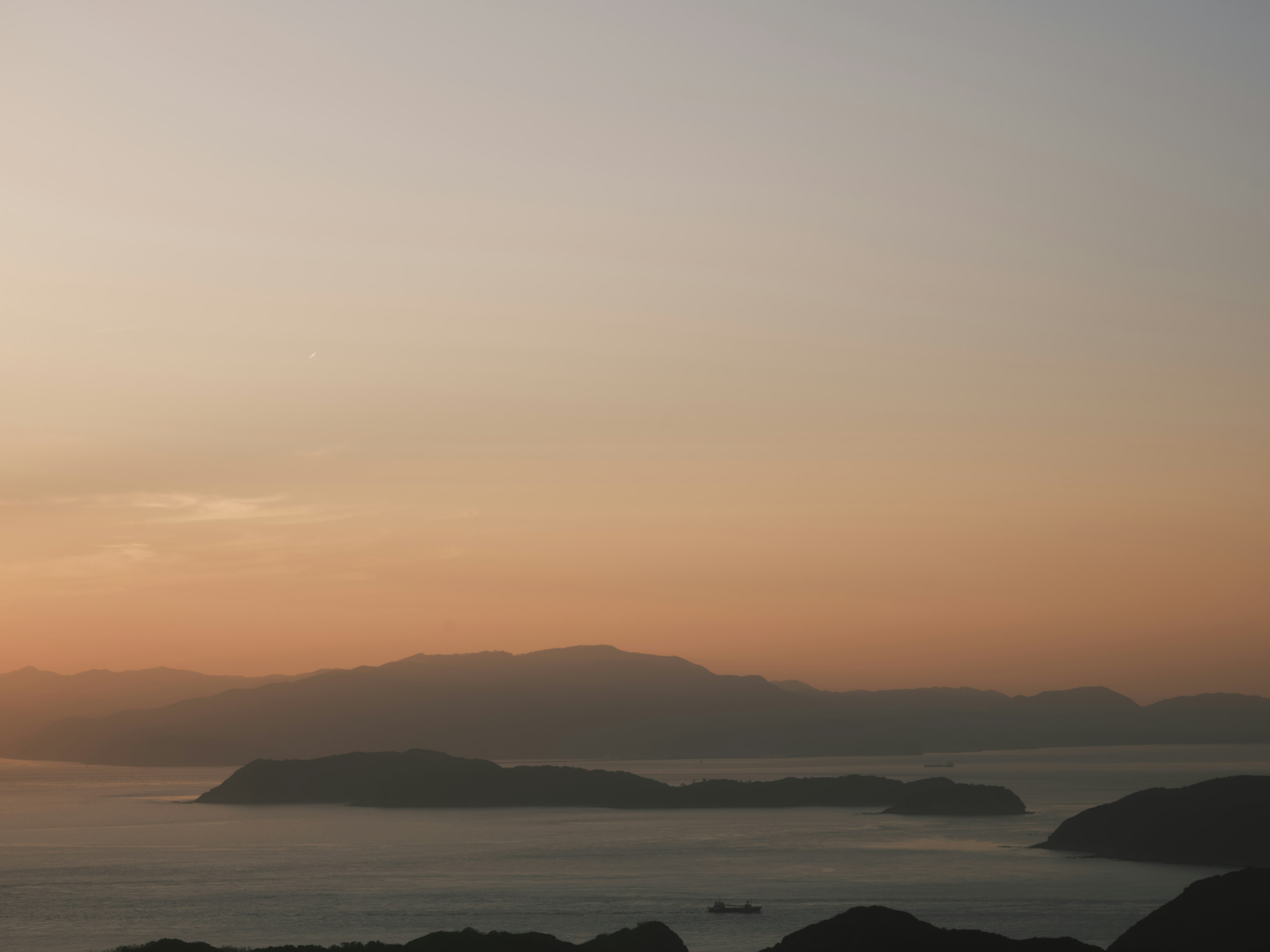 Ruhiger Sonnenuntergang über dem Meer mit mehreren Inseln am Horizont