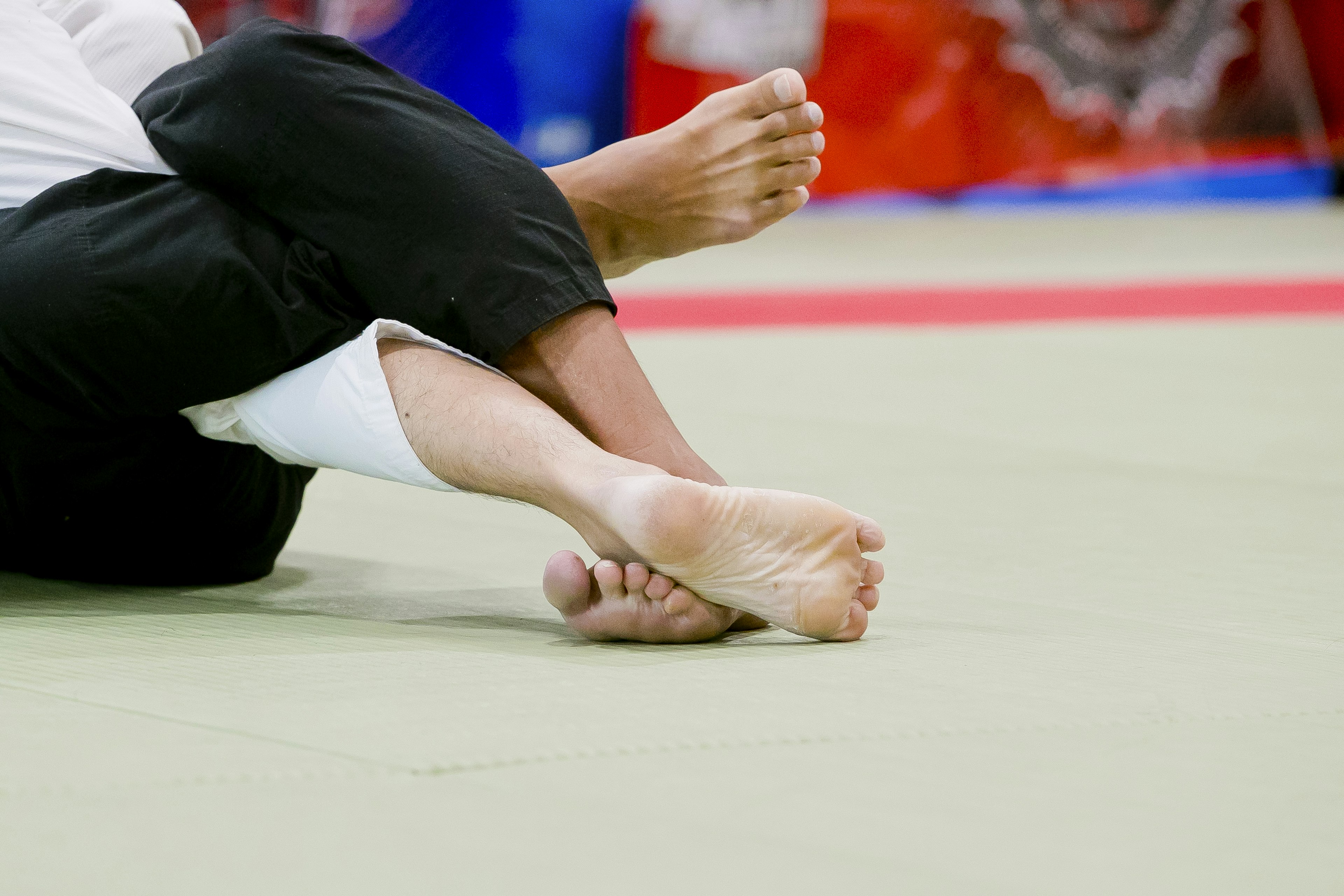 Dua kaki atlet judo yang saling terkait di atas mat