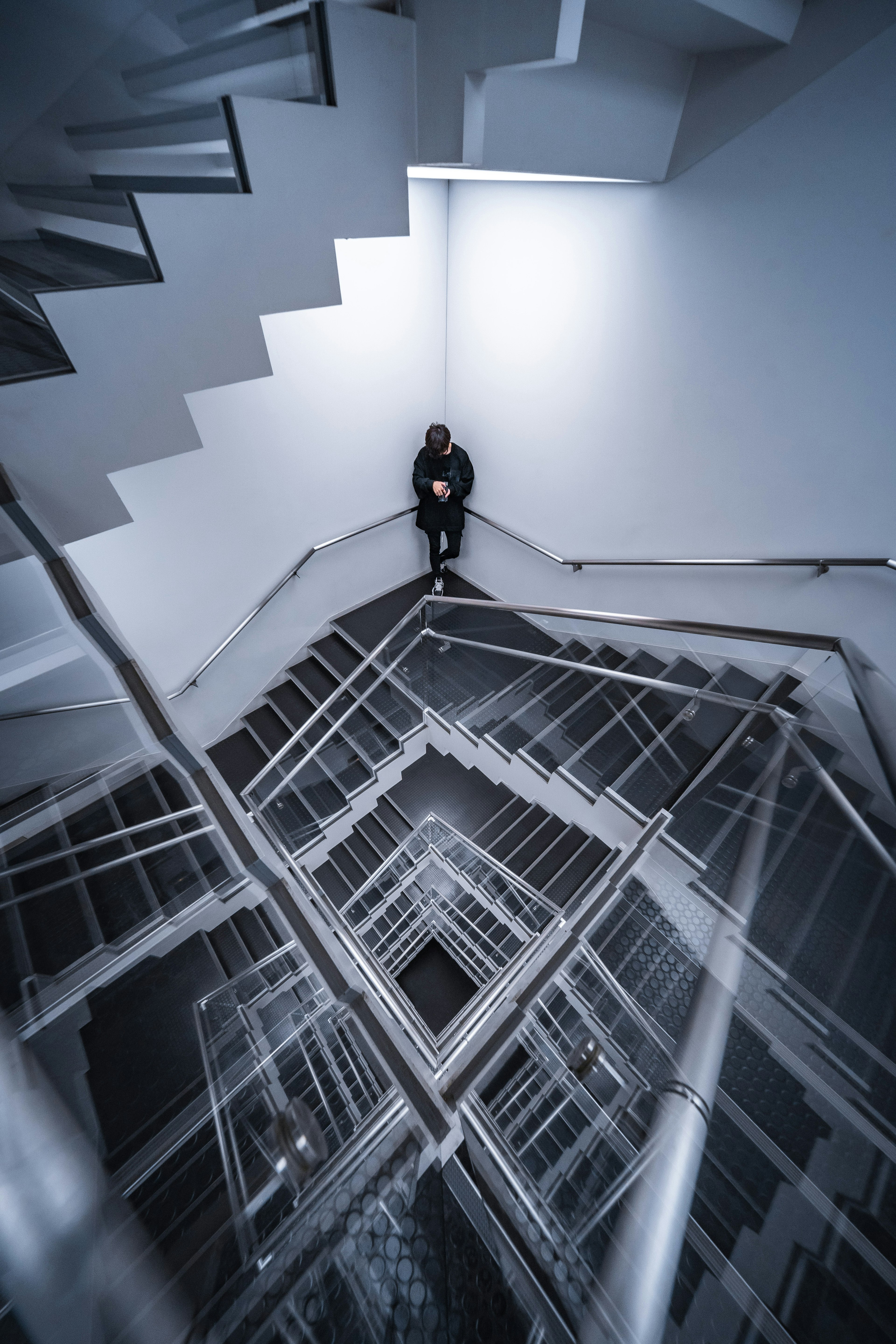 A person standing at the center of a modern spiral staircase