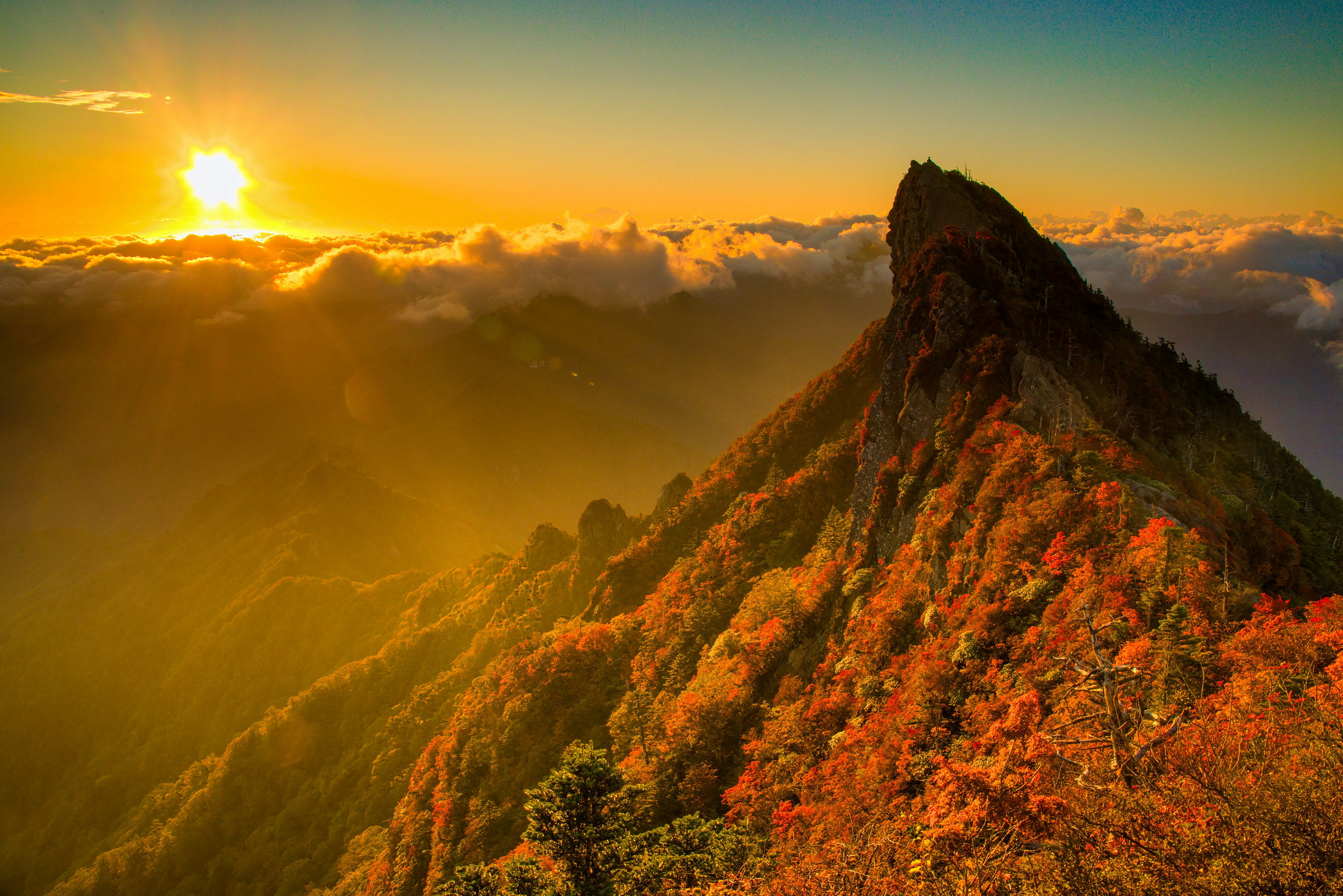 Atardecer sobre un pico montañoso con follaje de otoño