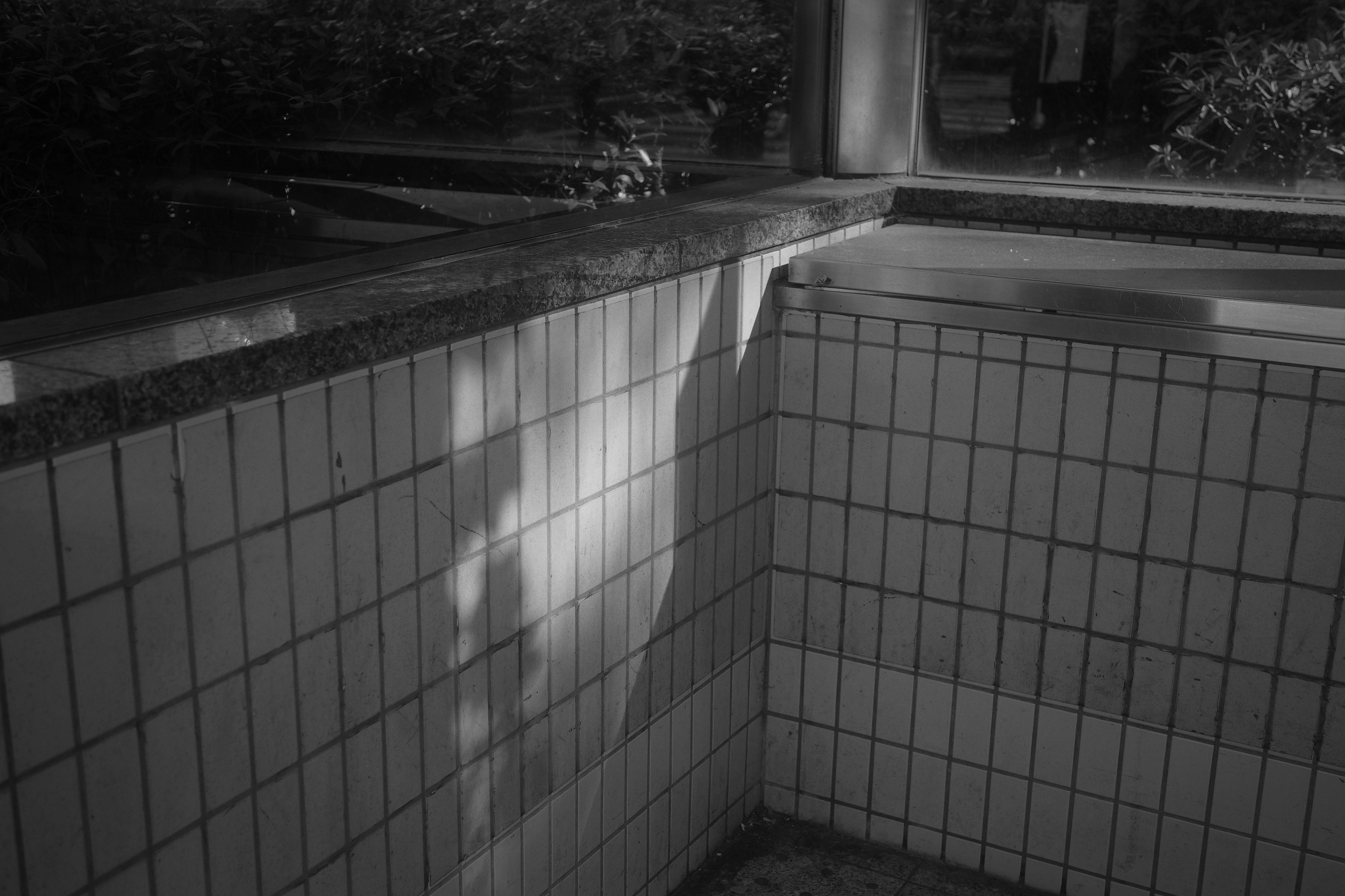 Contraste de luz y sombra en la esquina de una piscina de azulejos