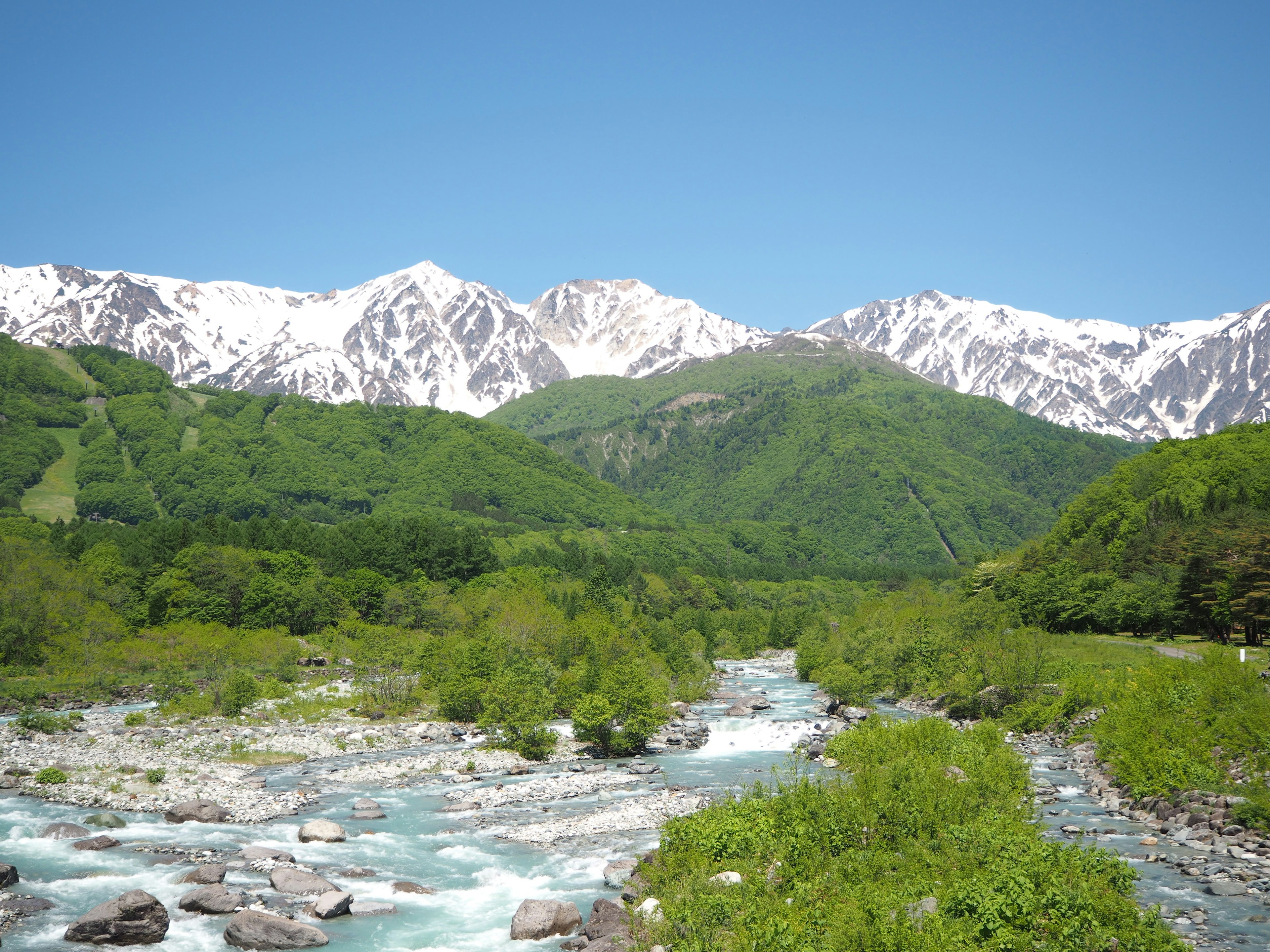 Vista panoramica di un fiume blu con montagne innevate vegetazione lussureggiante