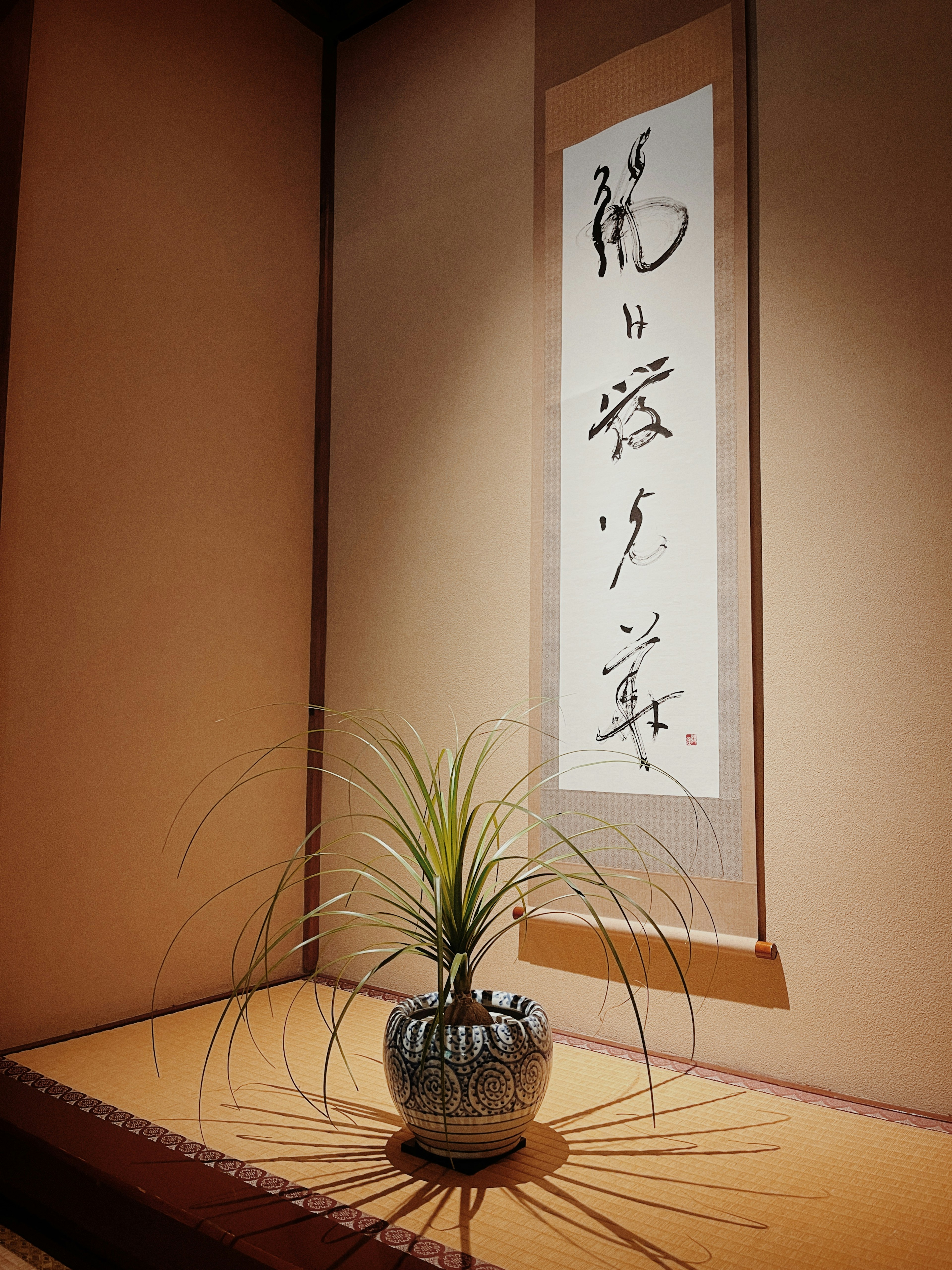 Un coin d'une pièce japonaise avec un rouleau de calligraphie et une plante en pot