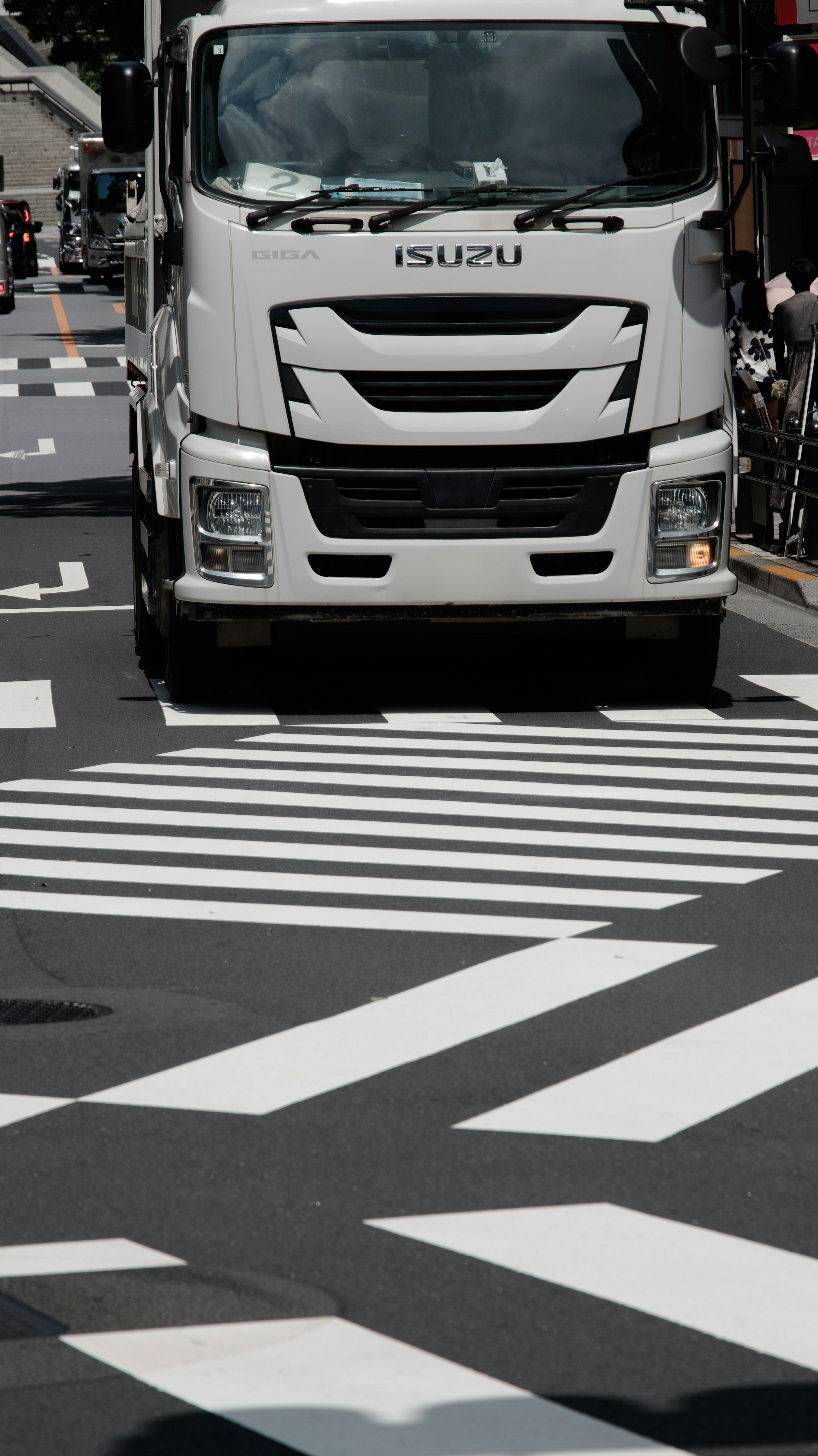 Weißer Lastwagen, der über einen Zebrastreifen in städtischer Umgebung fährt