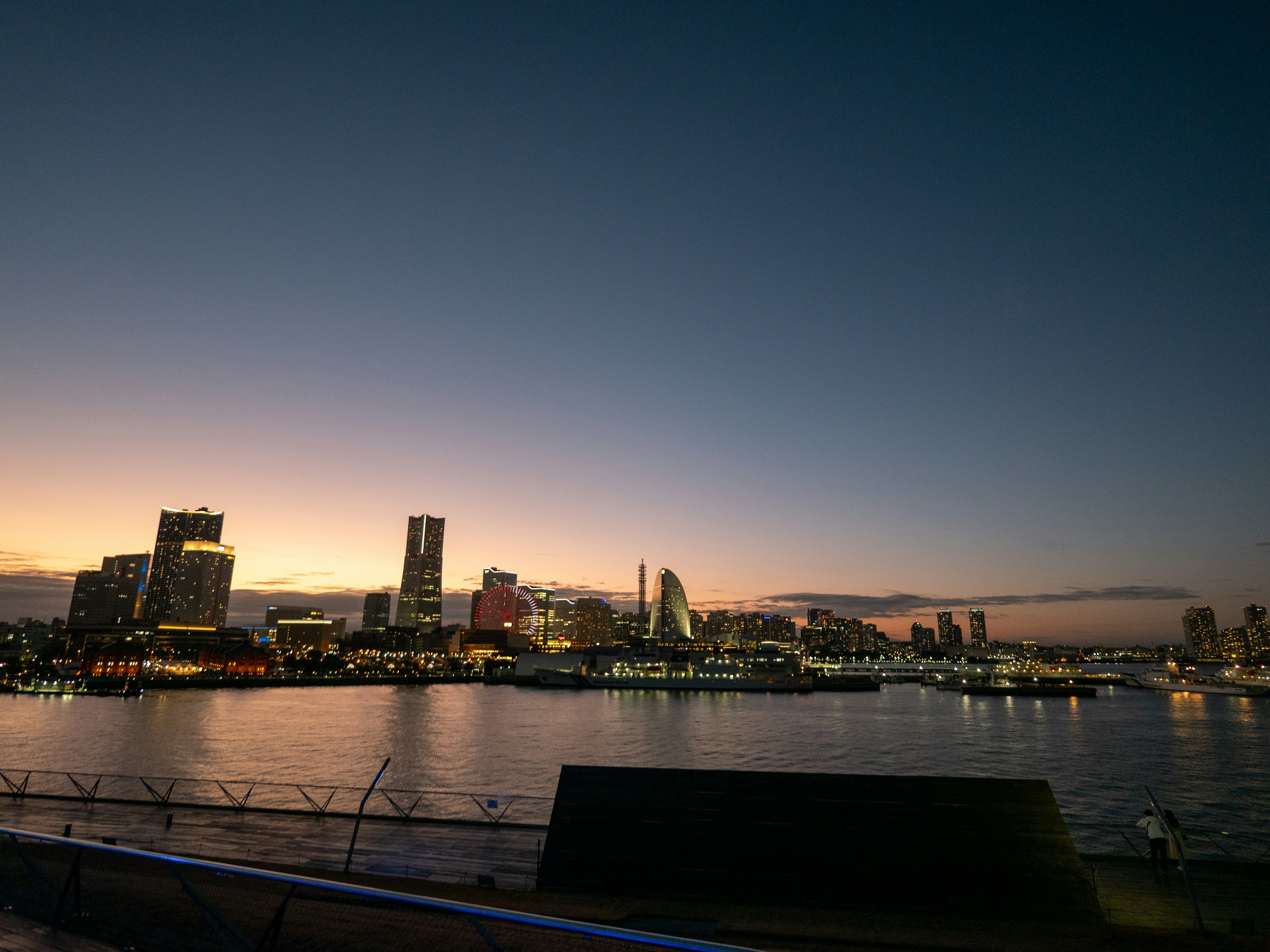 夕暮れ時の都市のスカイラインと静かな水面