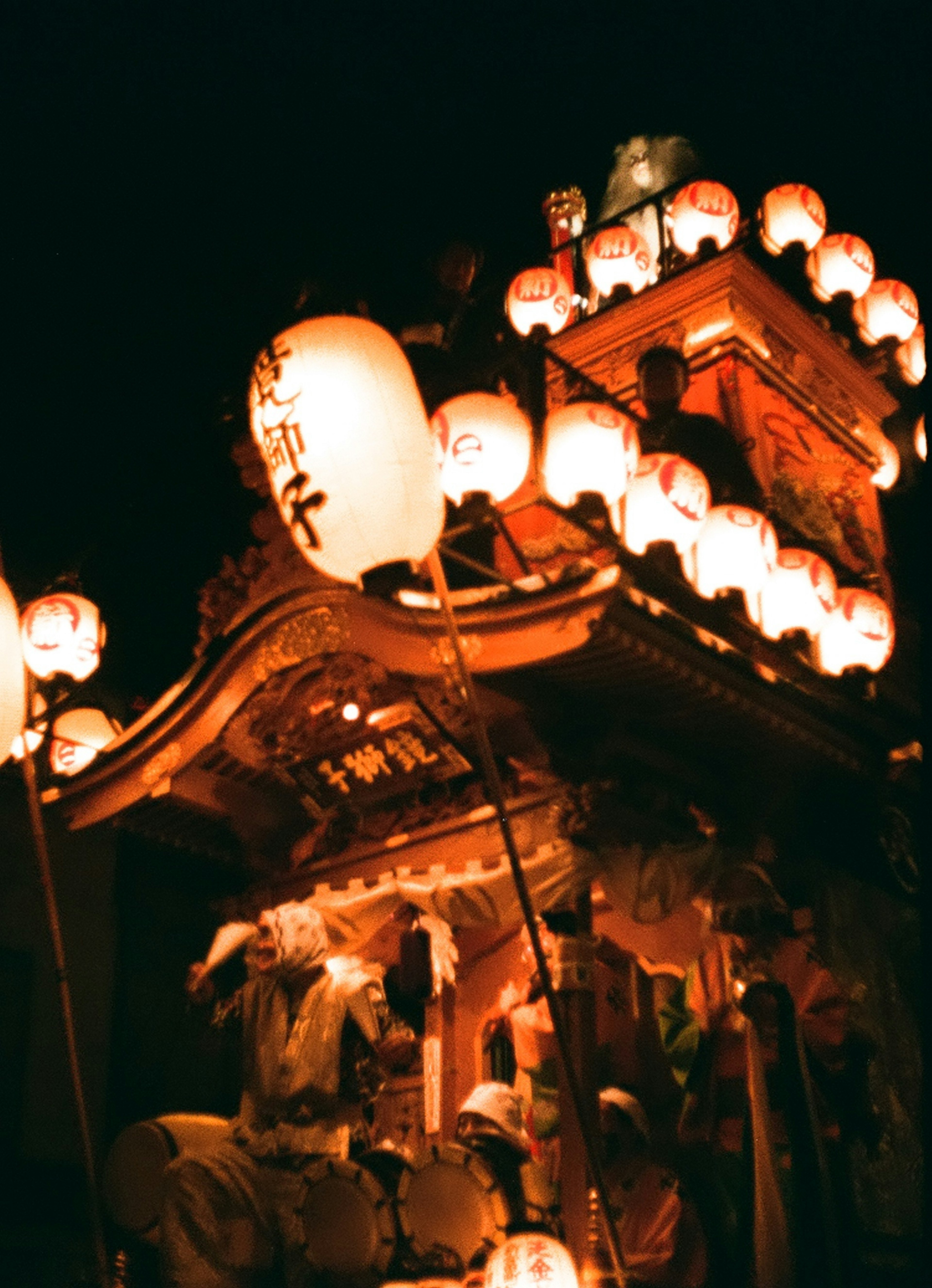 Beleuchtete Laternen und traditioneller Festwagen in der Nacht