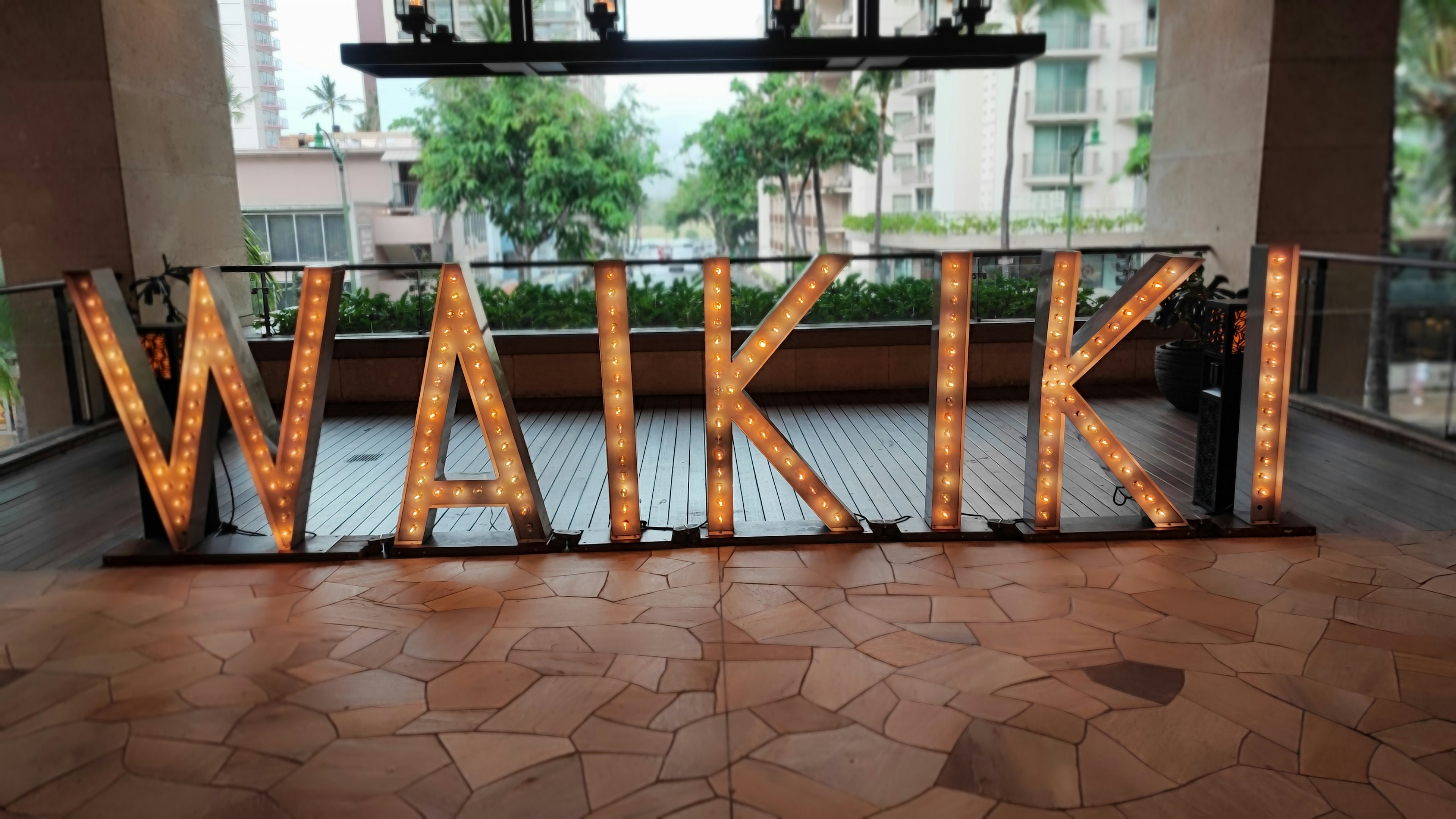 Brightly lit sign spelling 'WAIKIKI' in a modern indoor setting