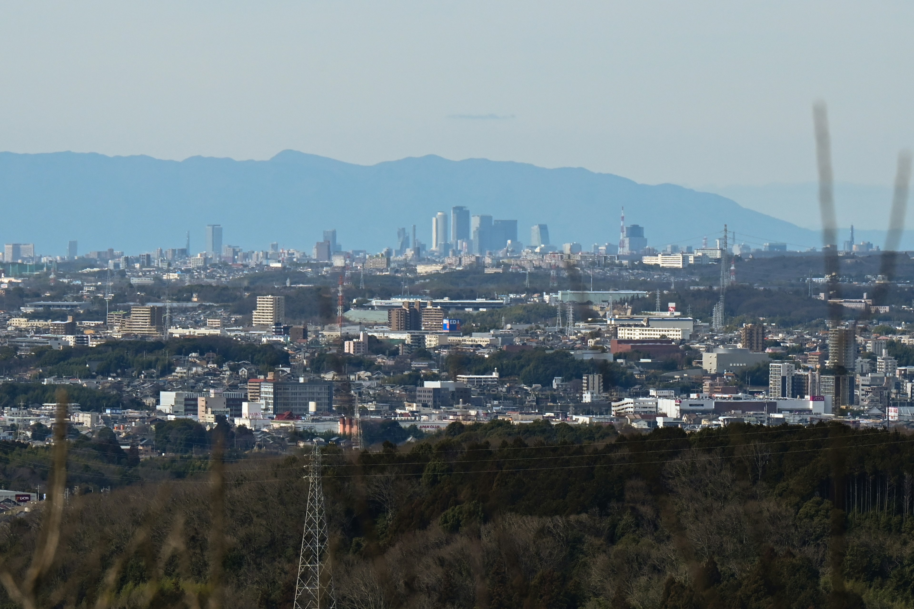 山の向こうに広がる都市の景観と電柱