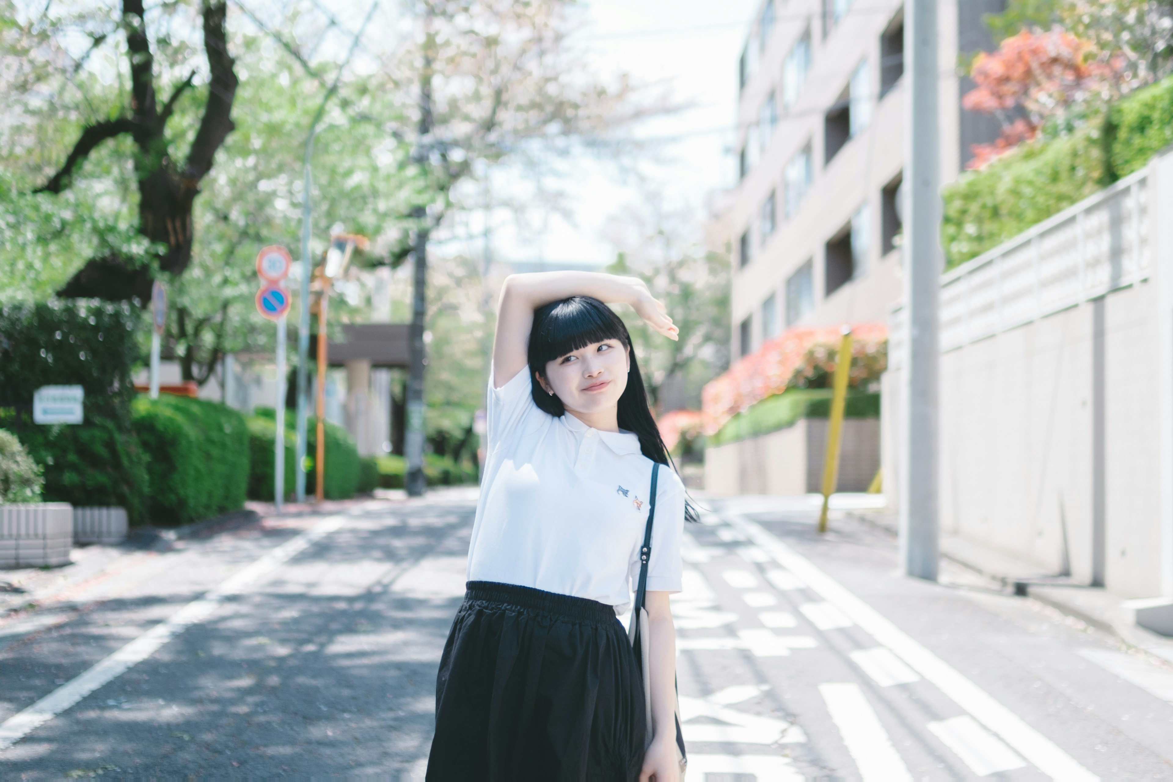 Young woman in white shirt and black skirt posing on a street