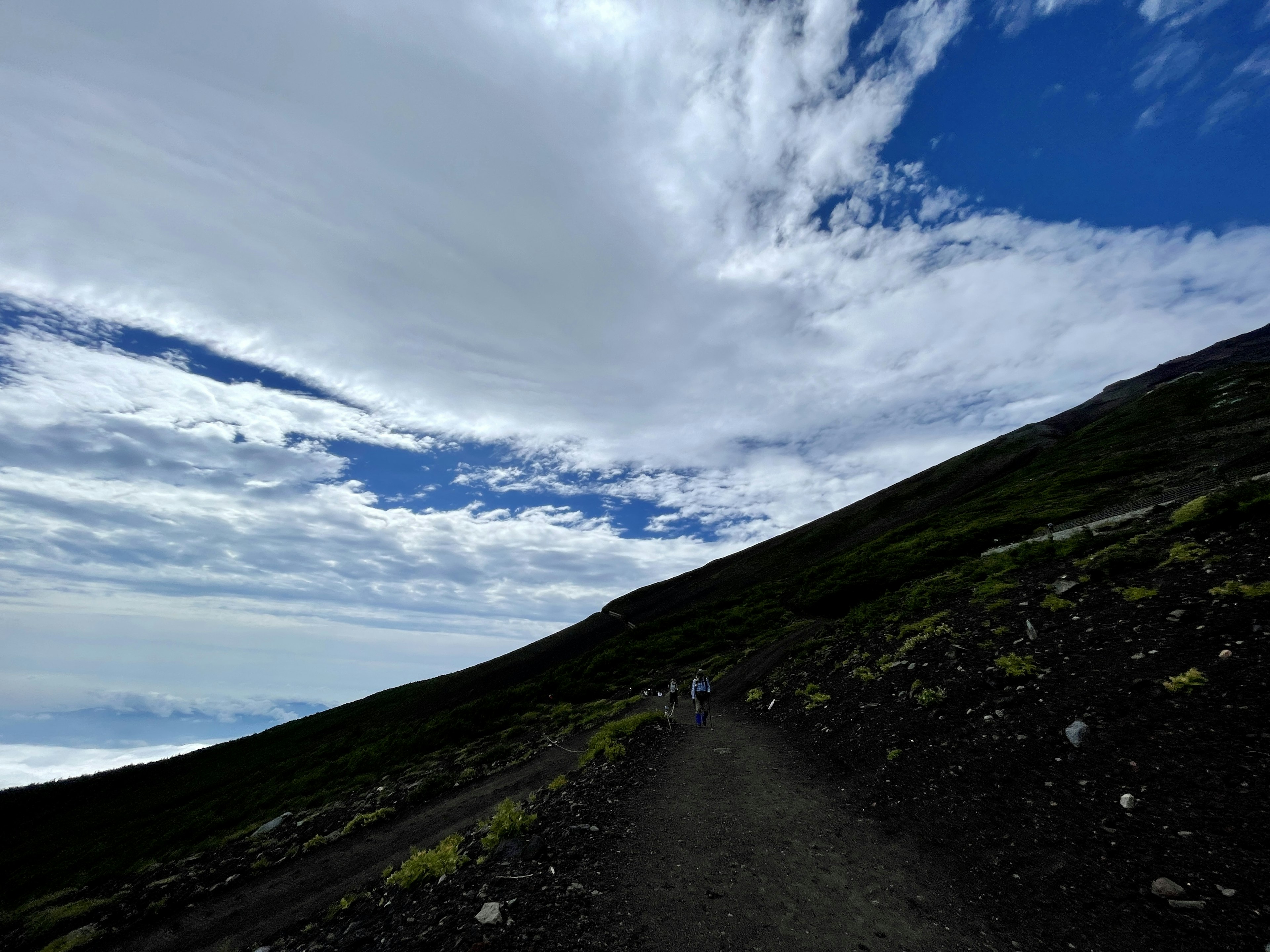 Sentiero di montagna panoramico con cielo blu e nuvole pendio verde e terreno roccioso