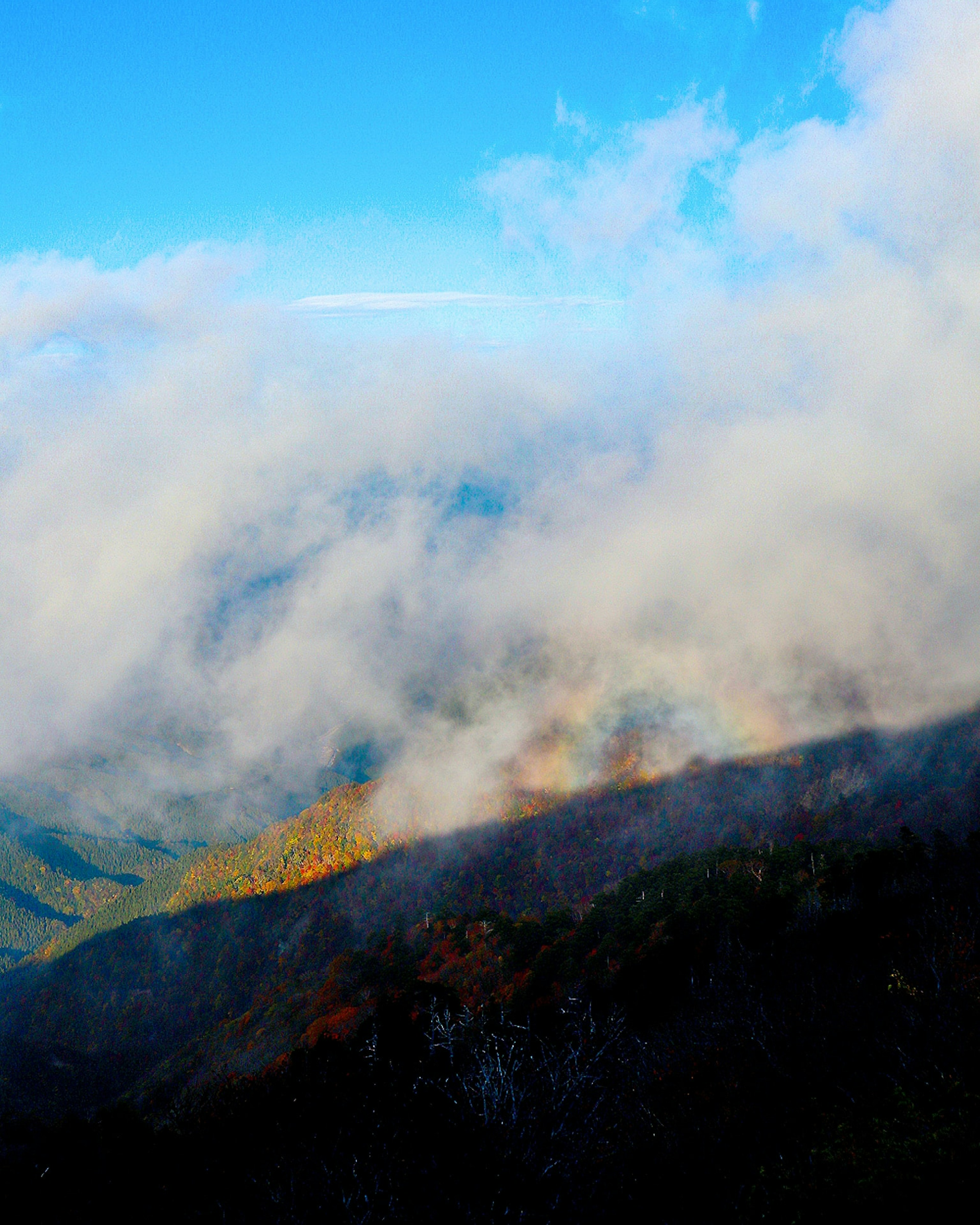 Paisaje montañoso envuelto en niebla con cielo azul