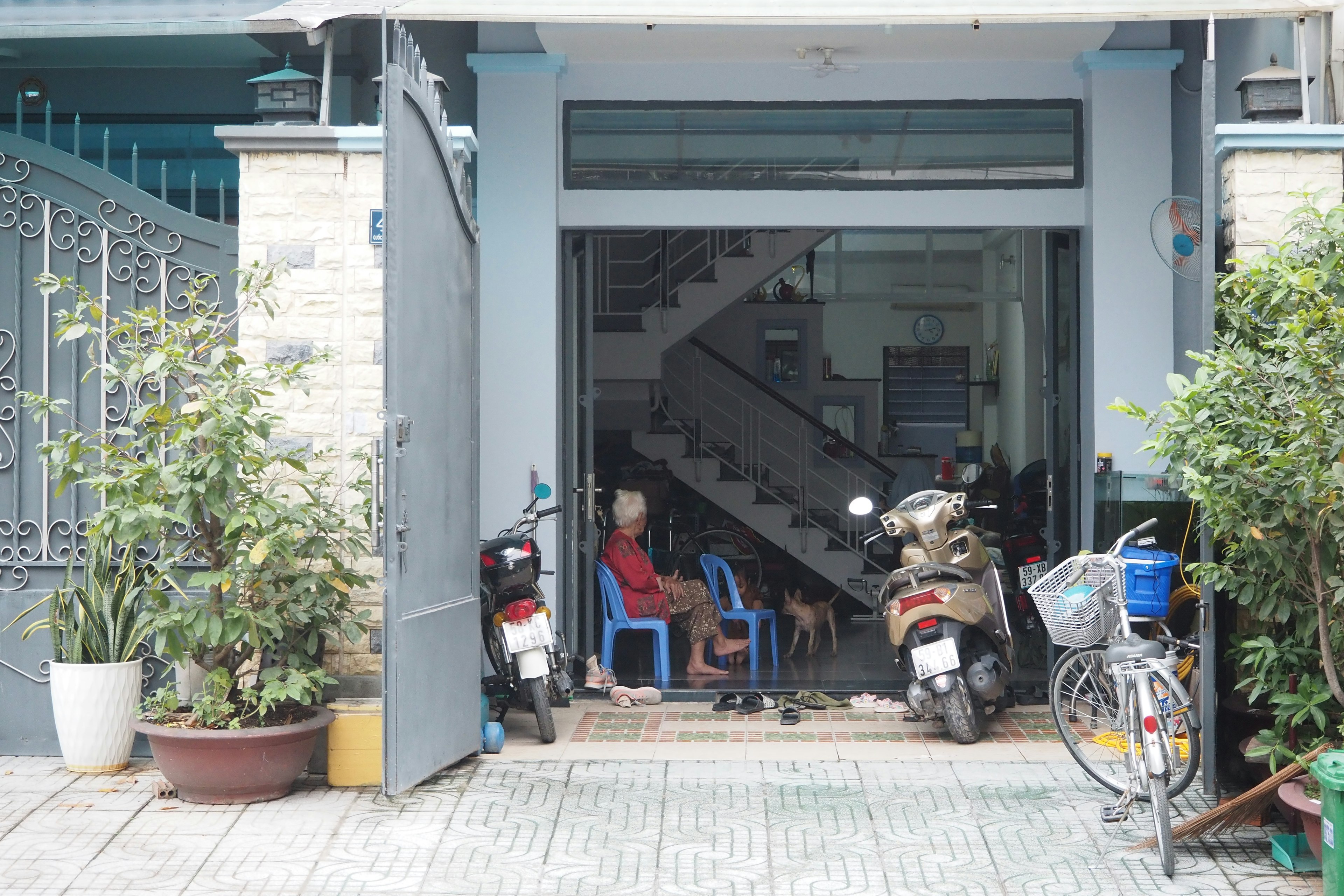 Entrée d'une maison avec des personnes assises sur des chaises bleues et un escalier visible