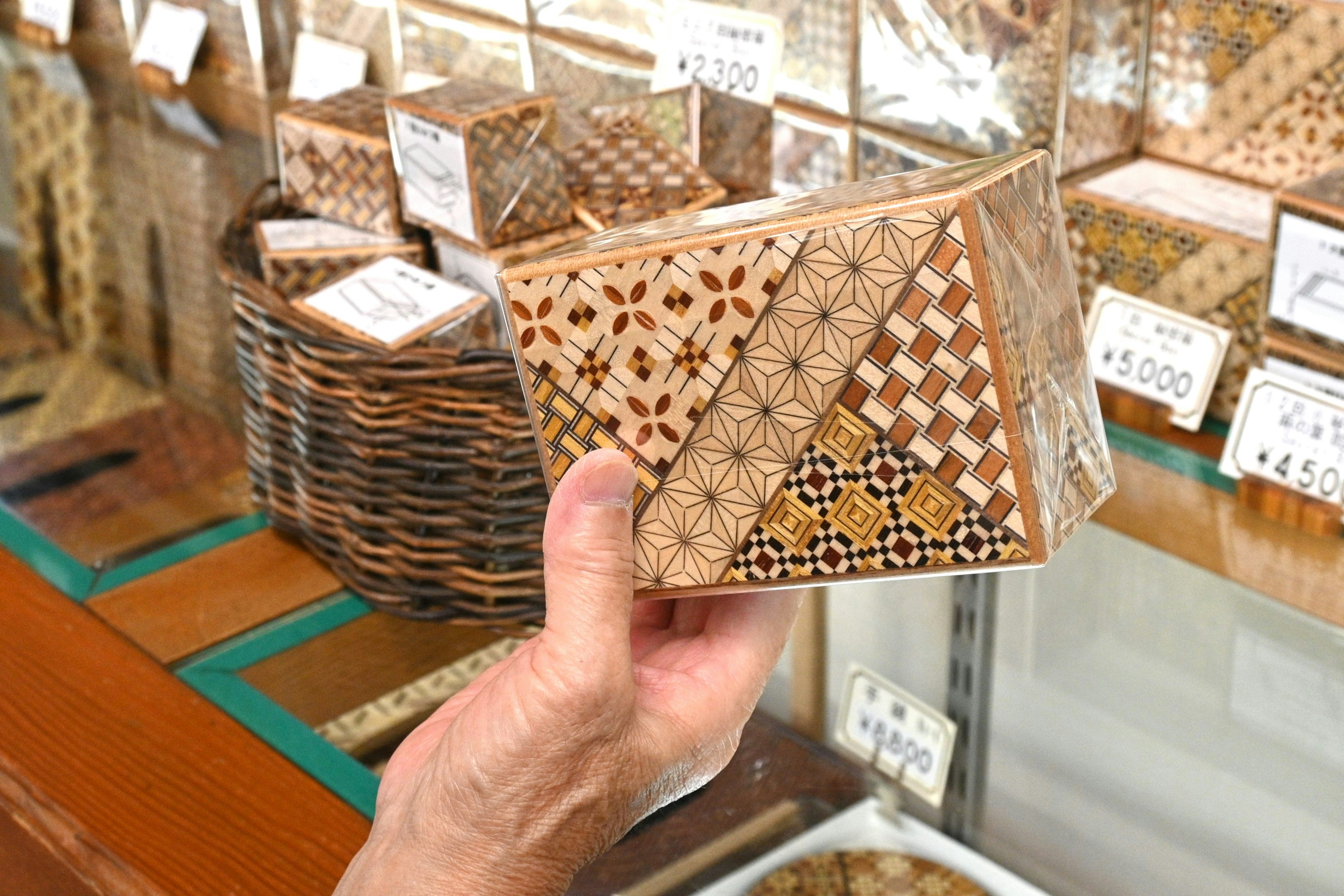 A beautifully crafted wooden box held in hand featuring intricate patterns and varying colors