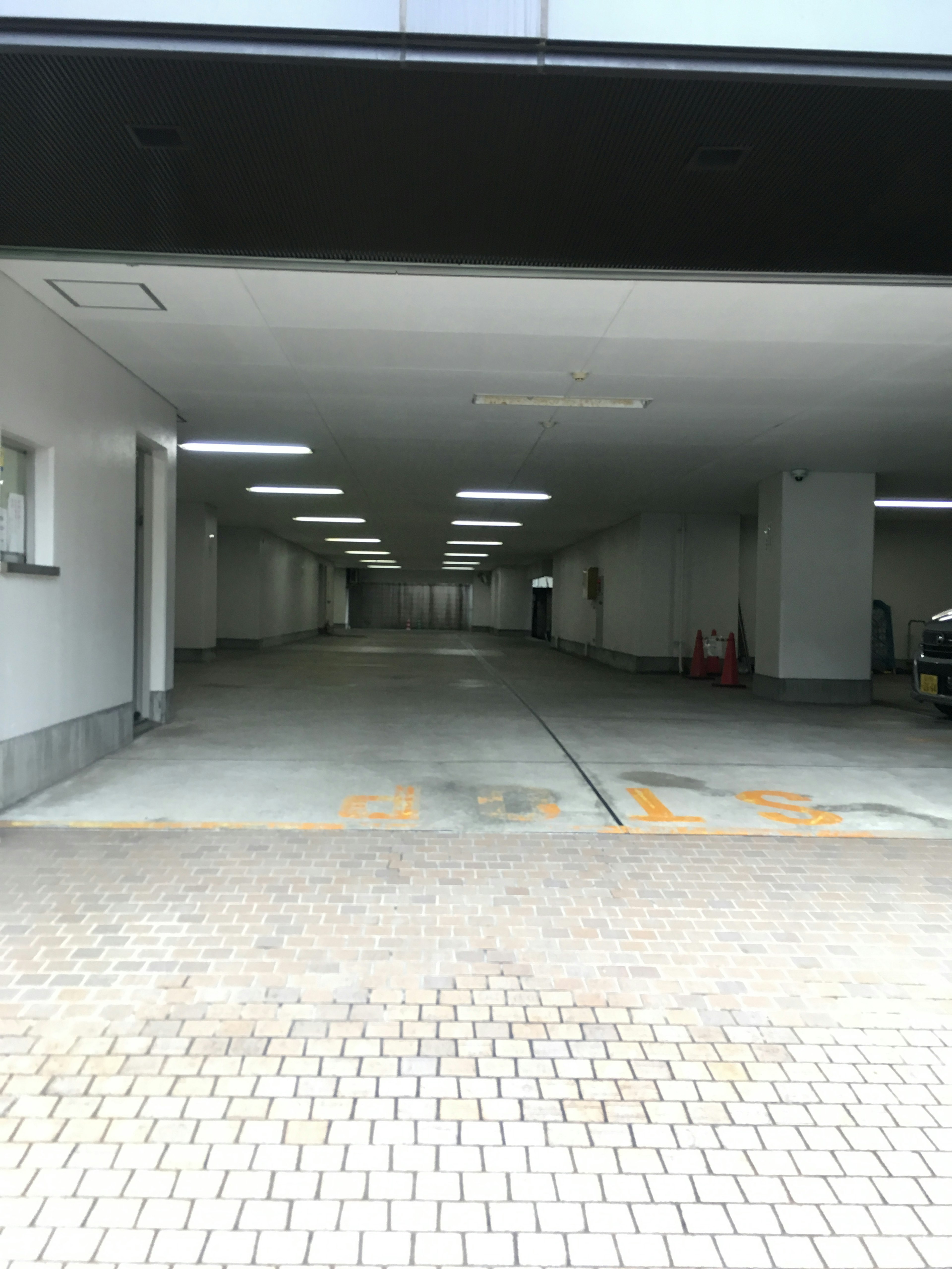 Spacious underground parking entrance with bright lighting and tiled floor