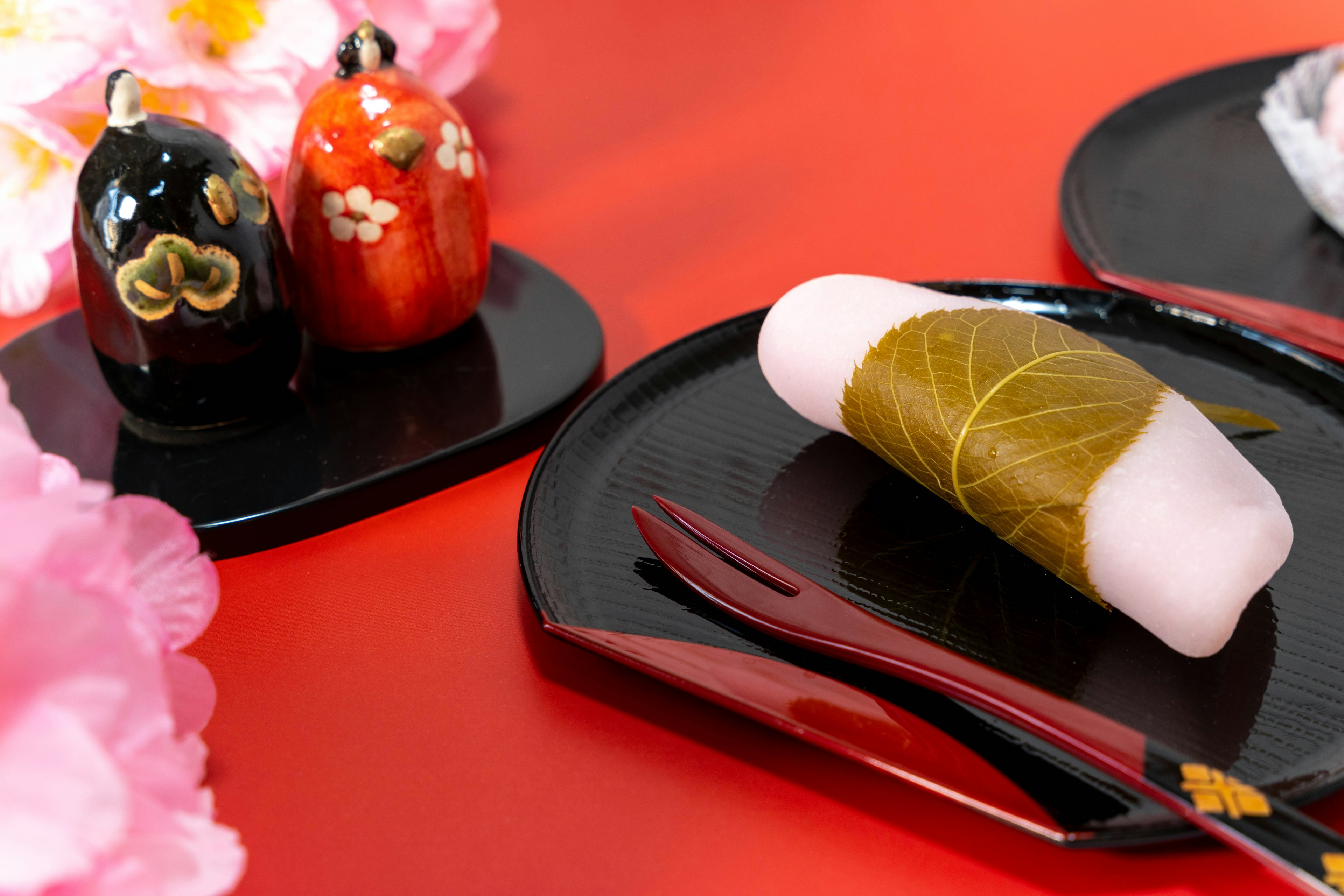 Traditional Japanese sweets on black plates with decorative figurines